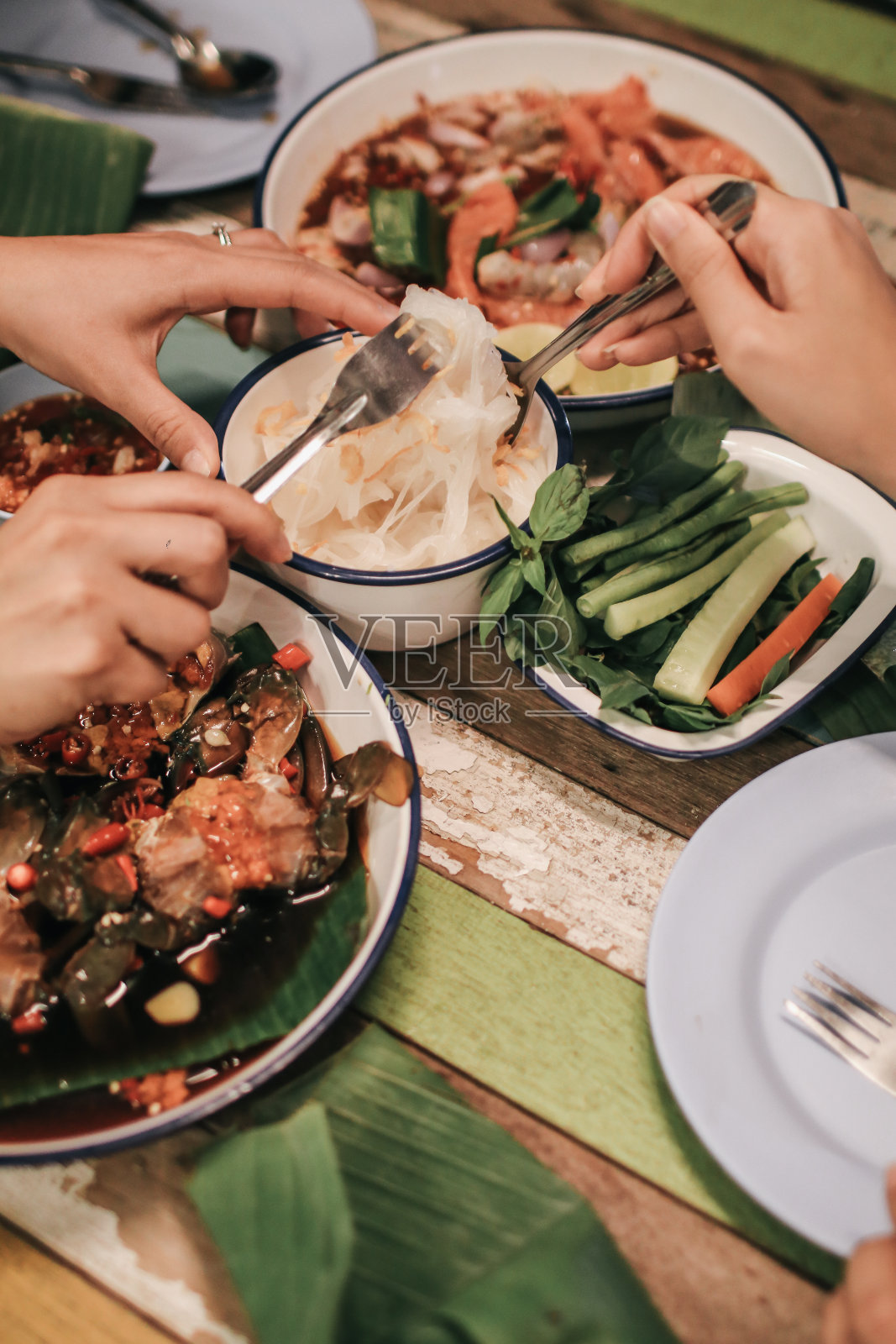 用手叉吃米粉并撒上炒蒜末，配以辛辣的木瓜色拉等菜肴照片摄影图片