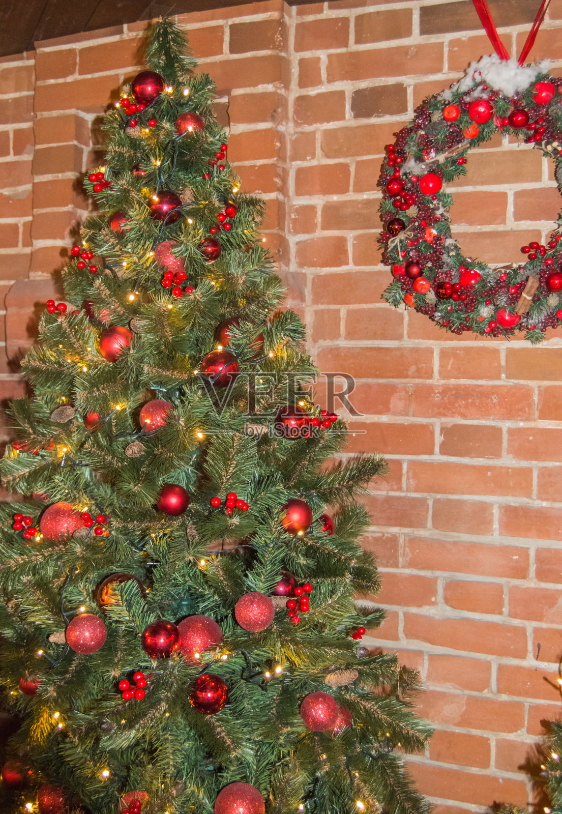 房子的红砖墙是为圣诞节装饰的。圣诞树上有花环和圣诞花环，用于家庭装饰，户外装饰照片摄影图片