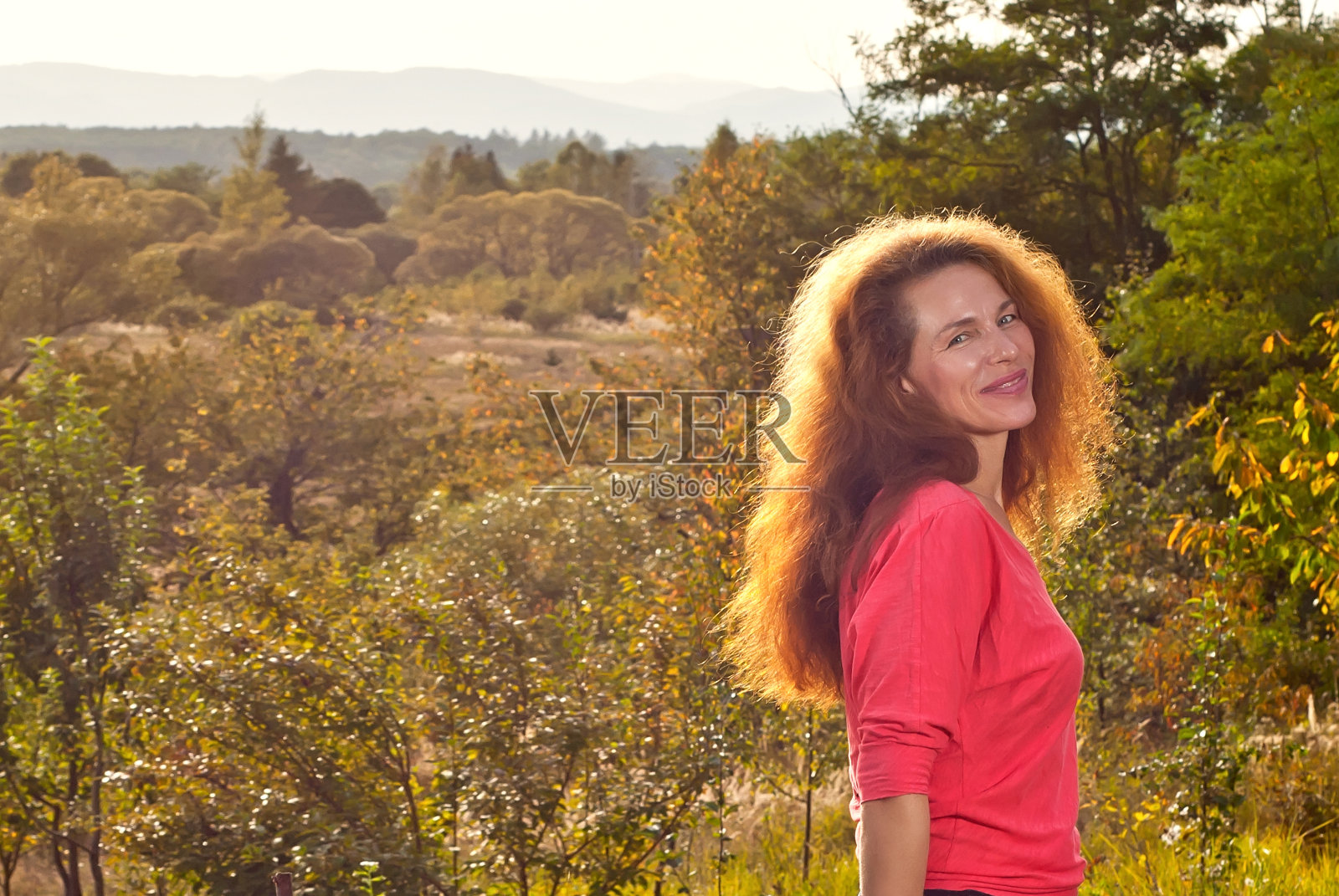 一个女人的自然肖像。快乐的女人在夏天的背景草，鲜花，绿色植物，森林。照片摄影图片