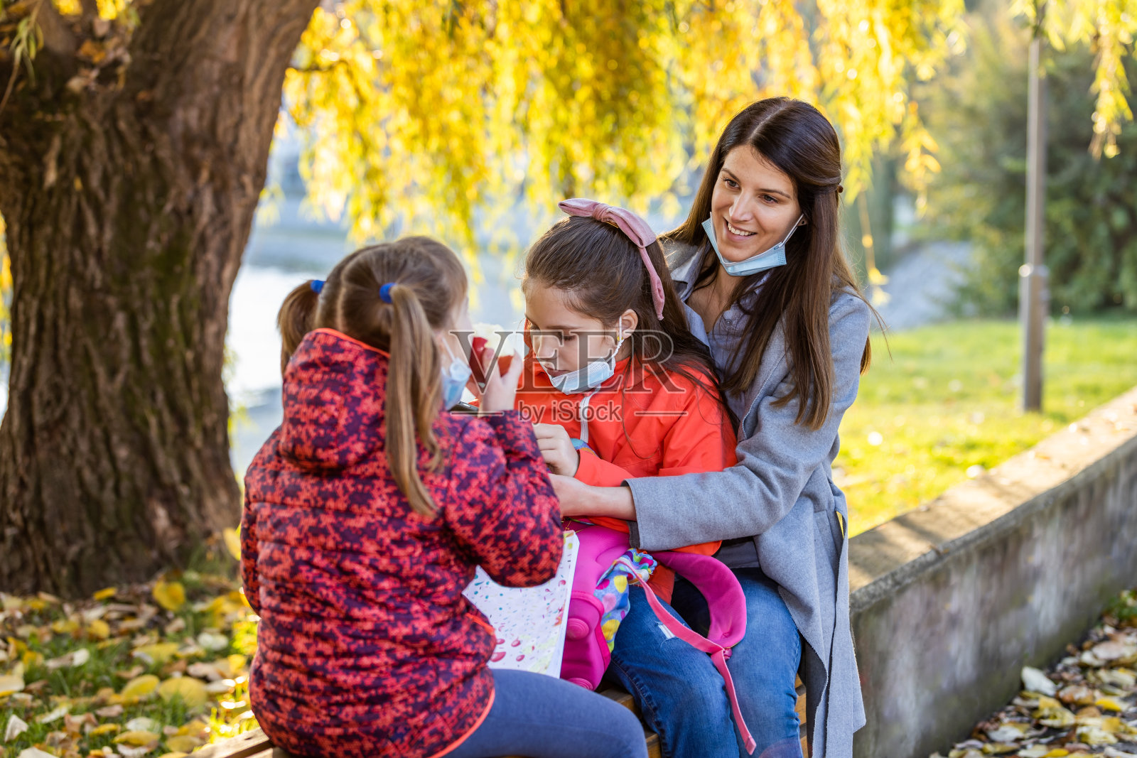 一位年轻的母亲，从学校回家与她的女儿享受公园照片摄影图片