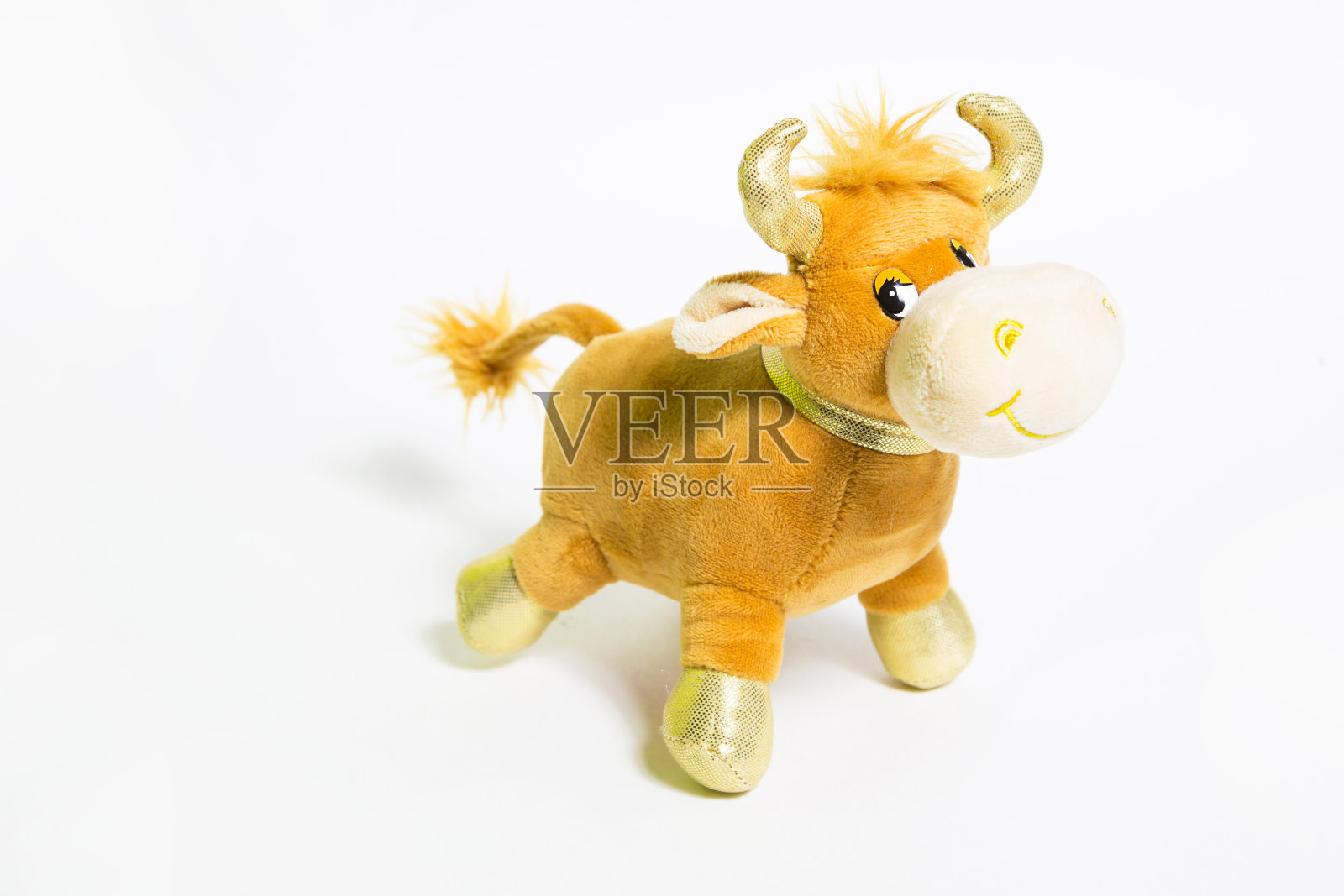 棕色毛绒玩具牛，金色的角和蹄在灰色的背景上。软年的象征，中国历法上的牛照片摄影图片