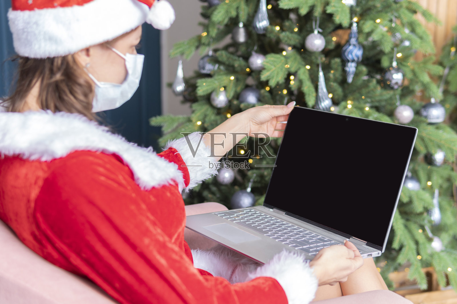 女人手打字电脑键盘上的书桌上办公概念办公室圣诞和新年快乐。一位穿着圣诞老人服装的年轻女子坐在电脑屏幕前照片摄影图片