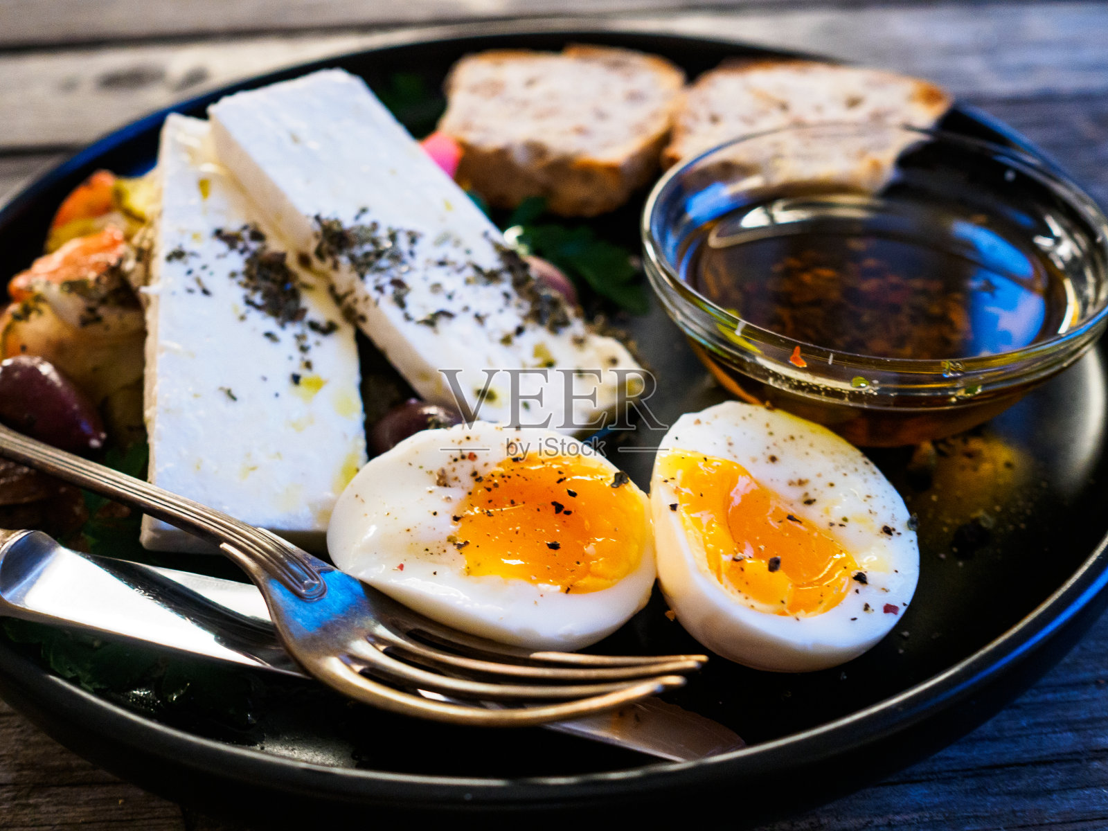 克里特岛盘子-新鲜的希腊沙拉，羊乳酪，西红柿，生菜，煮鸡蛋，黑橄榄和绿橄榄在黑色的盘子照片摄影图片