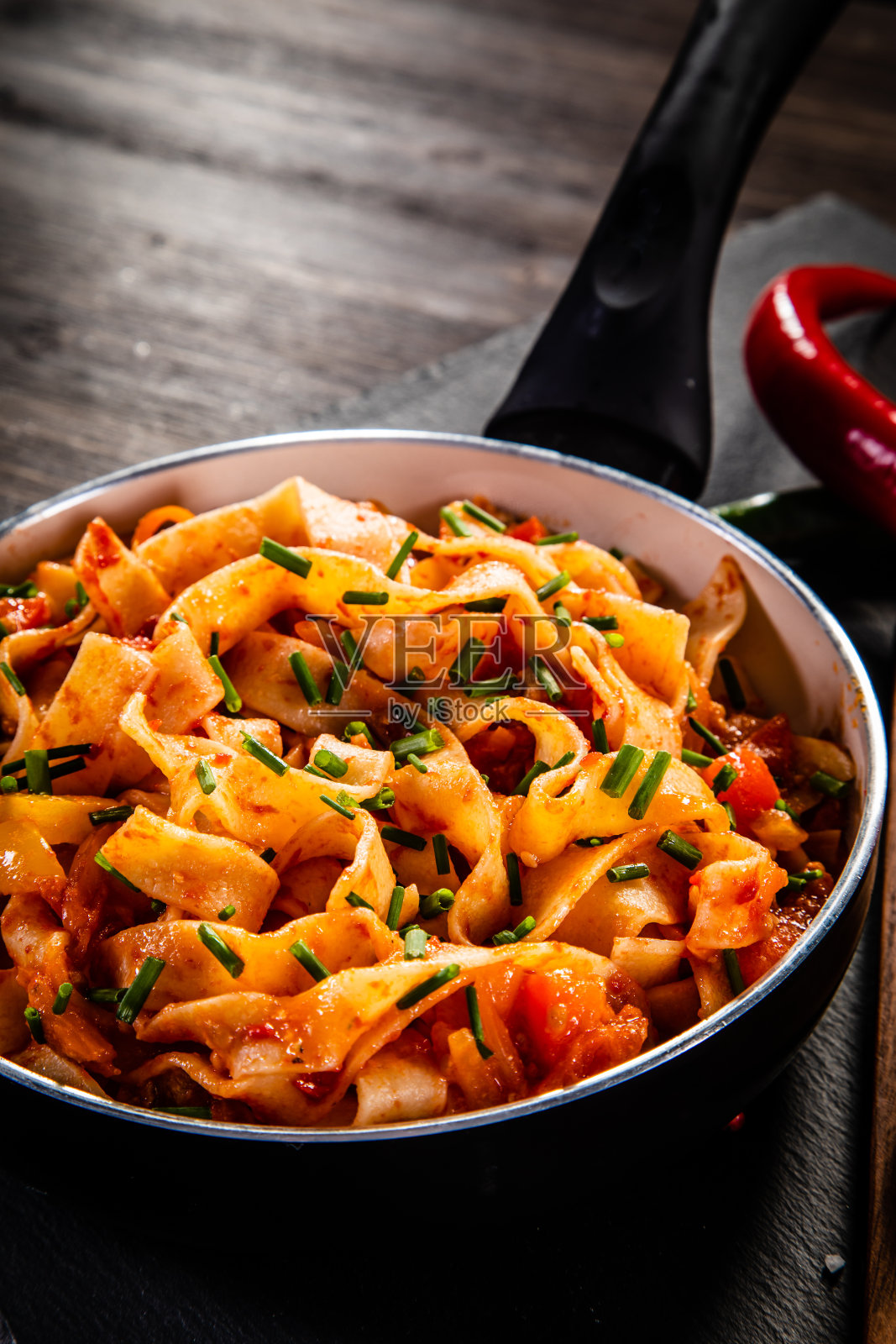 木桌上的黑石板上放着番茄酱、猪肉和帕尔马干酪意大利扁面照片摄影图片