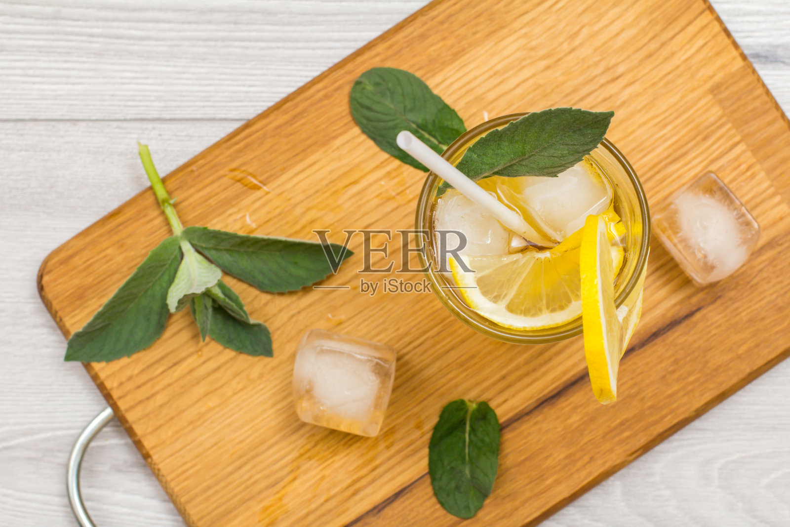 清凉的夏季柠檬水，冰和柠檬片，装饰薄荷叶在高脚杯。照片摄影图片
