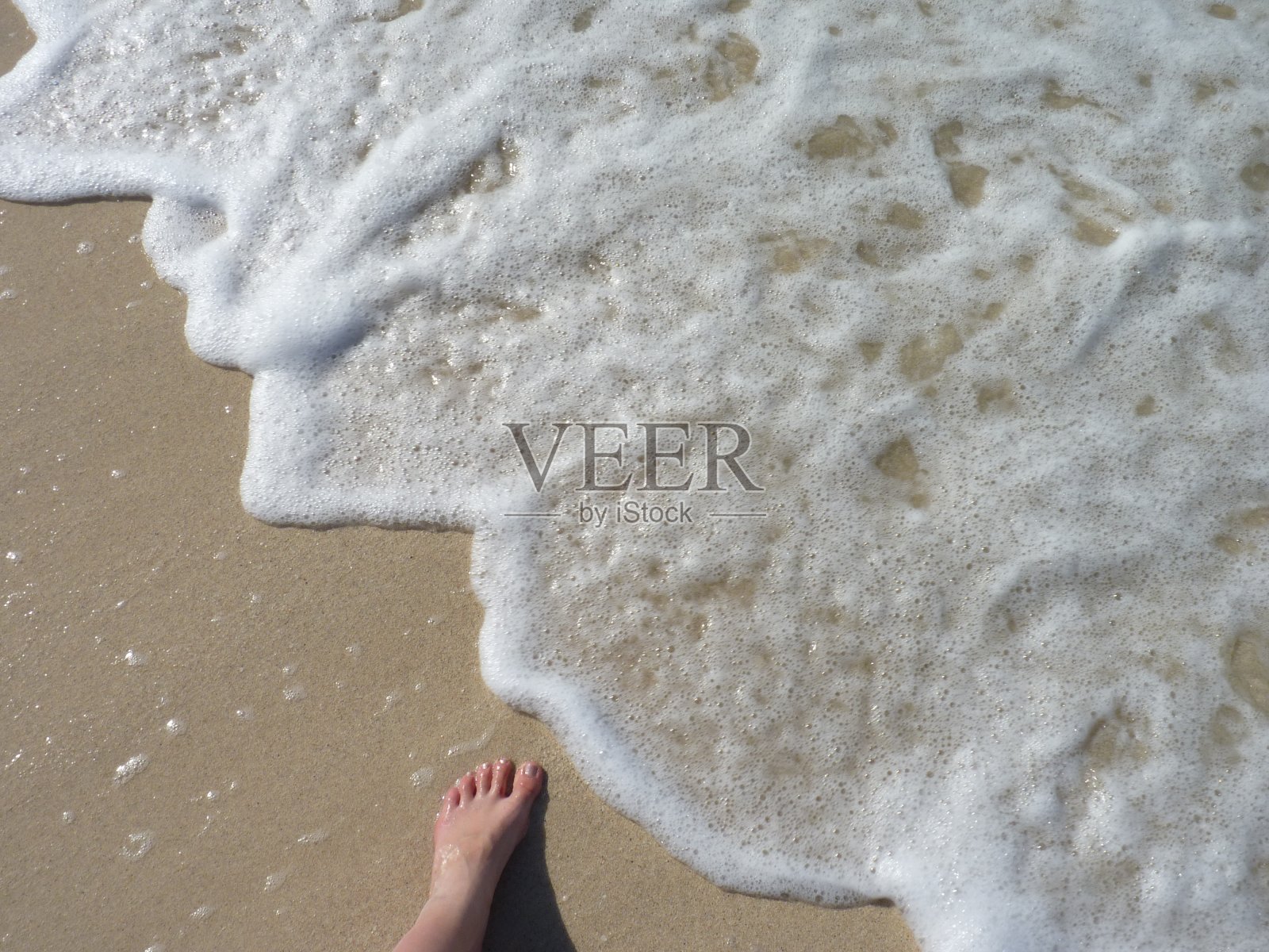 脚踏在靠近水的沙滩上照片摄影图片