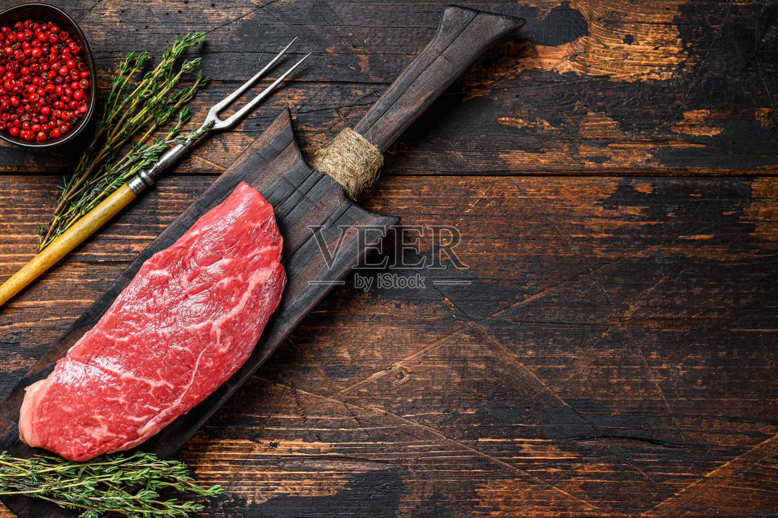切板上的生Striploin牛排，有大理石花纹的牛肉。深色木制背景。前视图。本空间照片摄影图片