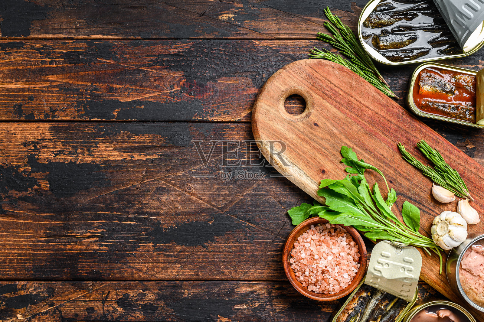 开罐保存与沙司，鲑鱼，鲱鱼，沙丁鱼，鱿鱼和金枪鱼。深色木制背景。前视图。本空间照片摄影图片