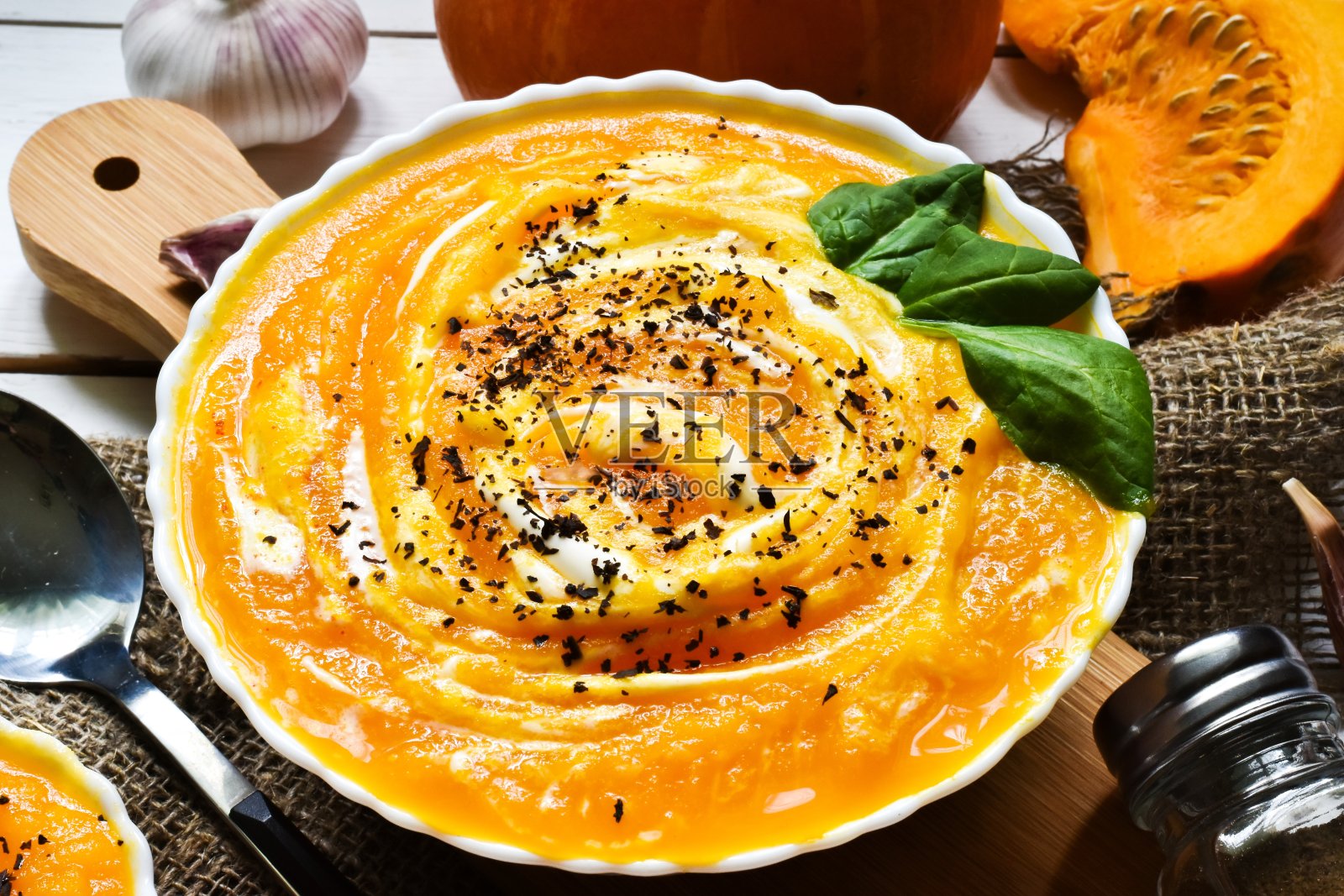 南瓜奶油汤在碗与香料在木背景。平铺，拷贝空间。特写镜头。照片摄影图片