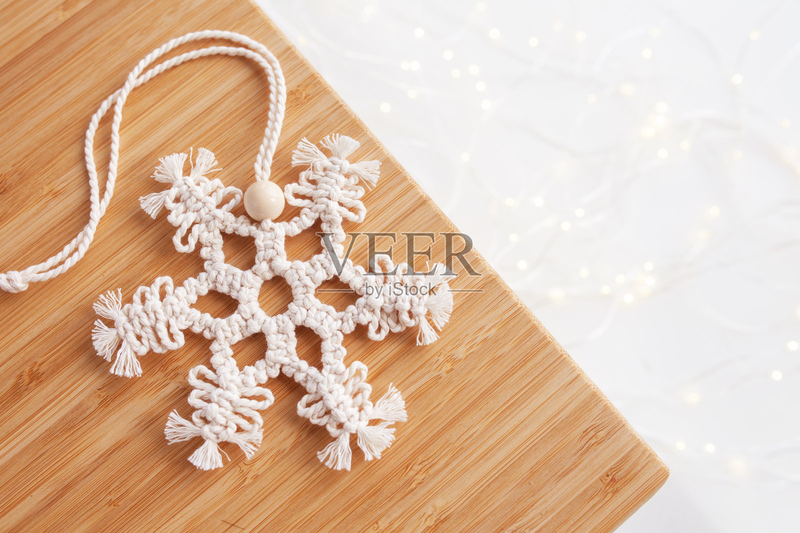 圣诞流苏花边装饰。圣诞的雪花放在木板上。天然材料-棉线，木珠。生态装饰、饰品、手工装饰。寒假和新年假期。本空间照片摄影图片
