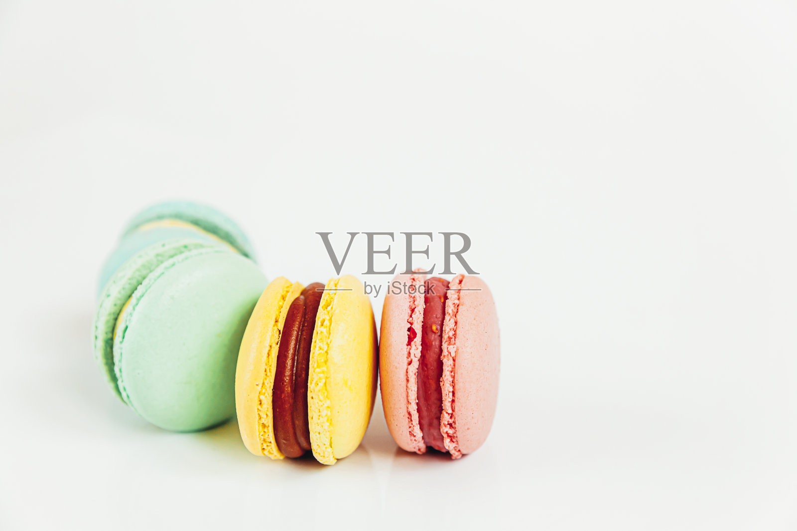 甜杏仁彩色柔和粉蓝色黄绿色马卡龙或马卡龙甜点蛋糕孤立在白色的背景。法国甜的饼干。简约的食品烘焙概念。平放俯视图，复制空间照片摄影图片