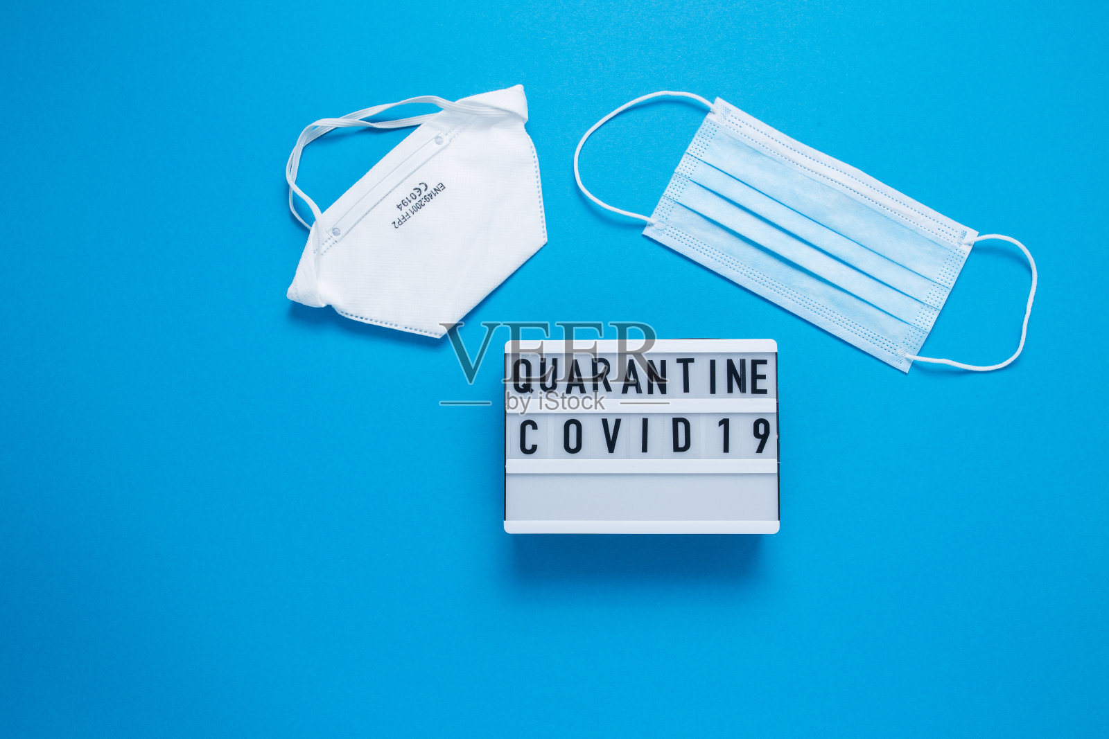 蓝色背景题词COVID-19。带题字的立方体。碑文隔离。碑文隔离。蓝色医疗面具照片摄影图片