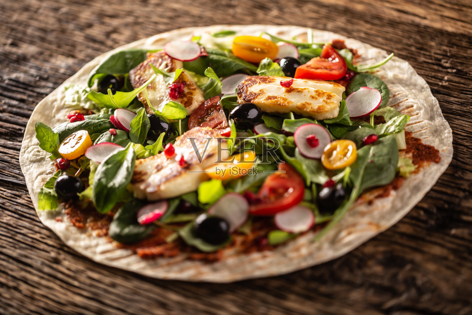 打开顶部的素食玉米饼与沙拉，小萝卜，奇瑞番茄，橄榄，石榴和烤哈露米奶酪。照片摄影图片