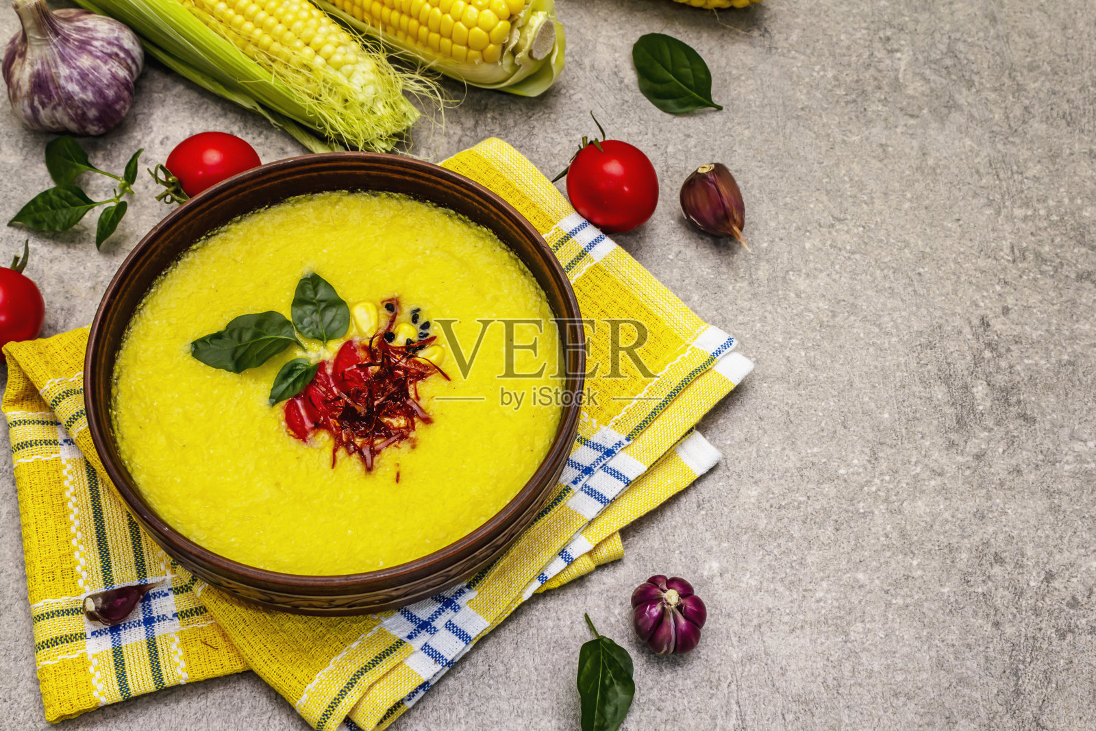 玉米奶油汤配新鲜蔬菜，香草和香料。经典的秋季热菜，石头混凝土背景照片摄影图片