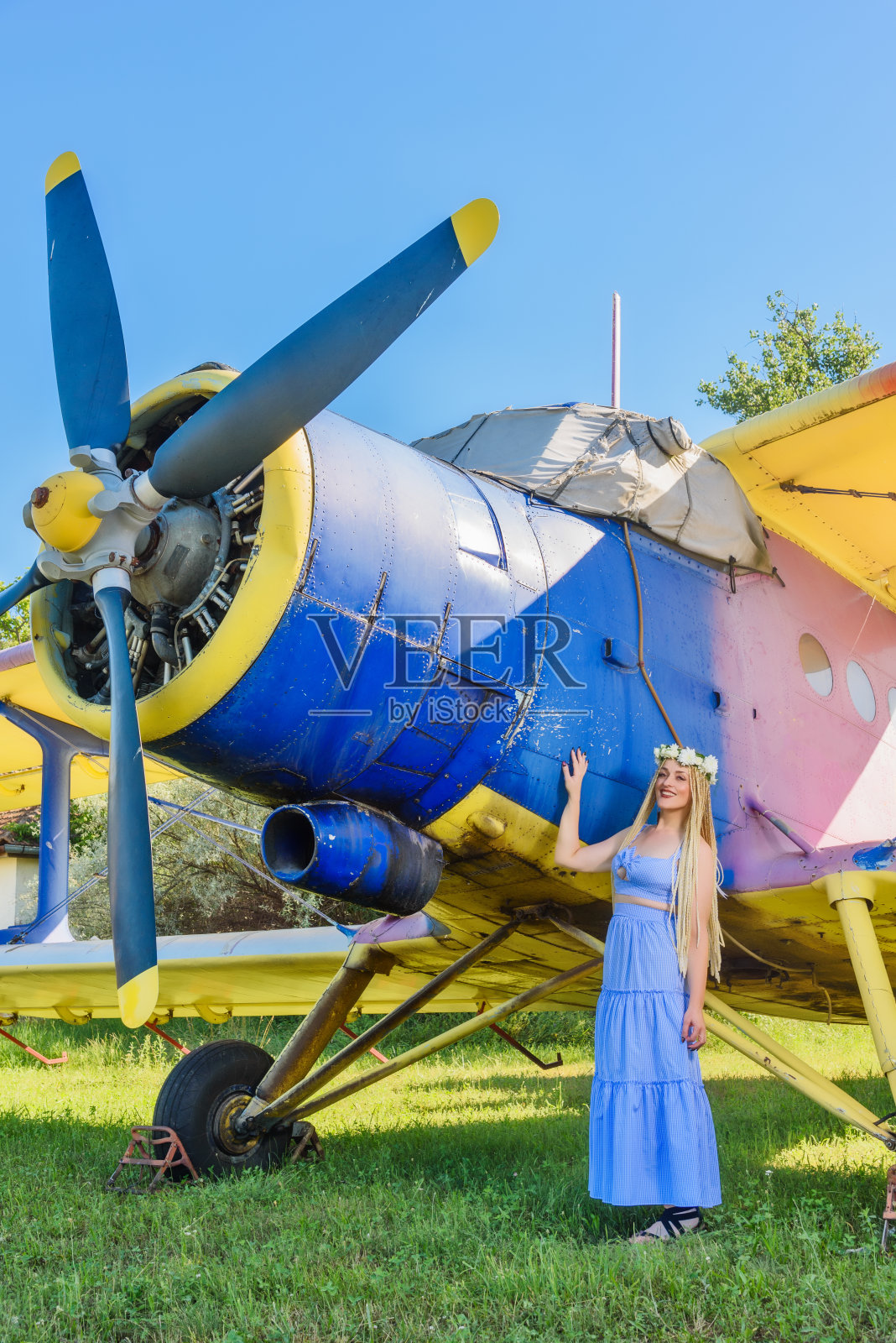 一个可爱的女人站在一架废弃的飞机旁。戴花环的妇女头上戴着花环的妇女照片摄影图片