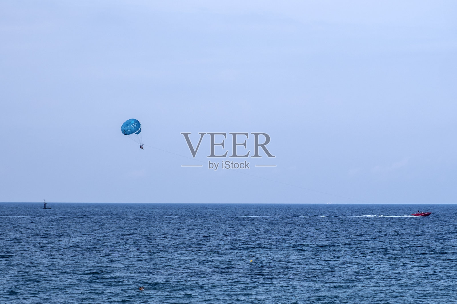 水上滑翔伞娱乐——在暑假里在船后面用降落伞飞行。以蓝天为背景，在大海上滑翔的游客。照片摄影图片