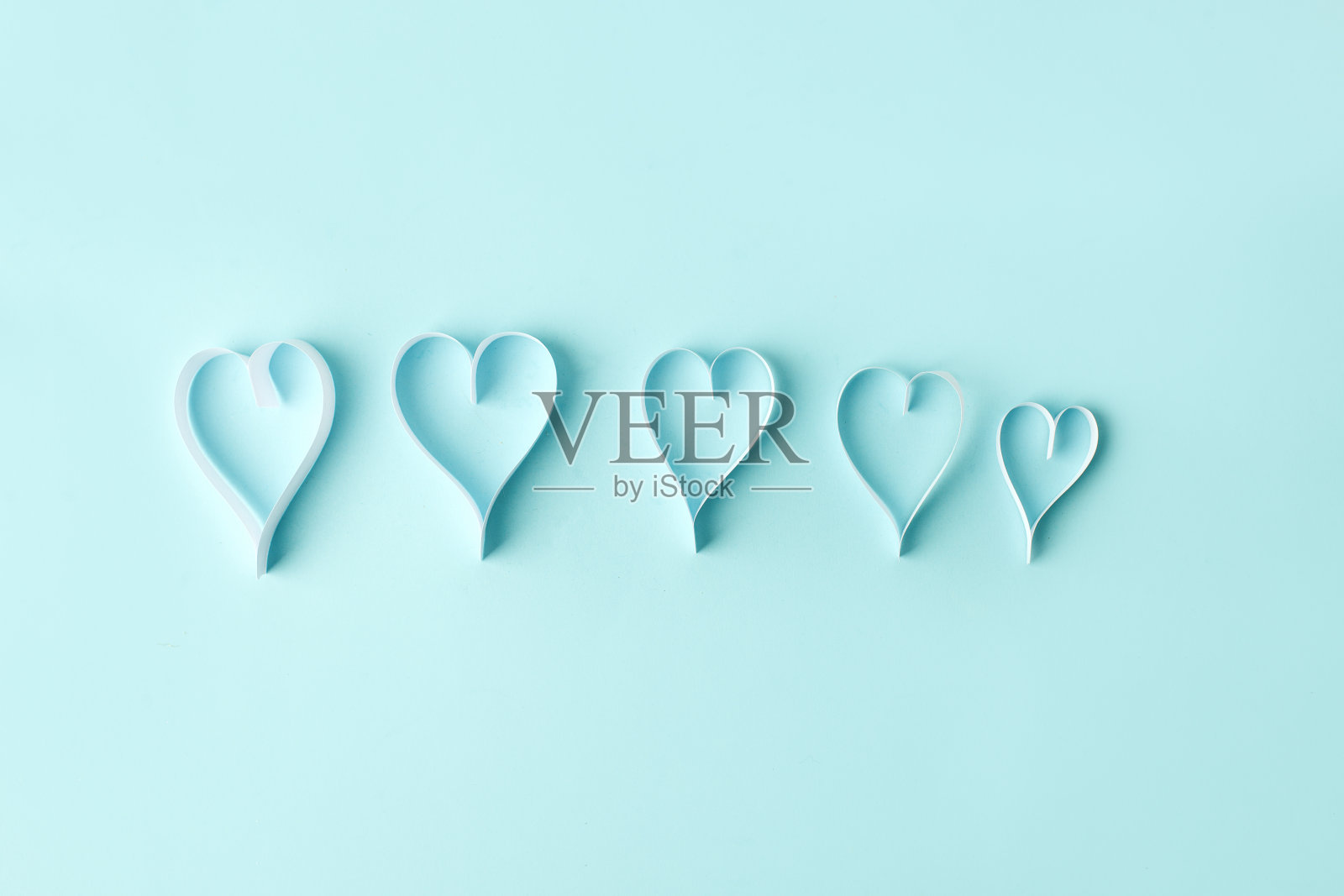 蓝色粉彩背景上的一排纸心。抽象的背景与剪纸形状。圣瓦伦丁，母亲节，生日婚礼贺卡，邀请，庆祝概念，横幅照片摄影图片