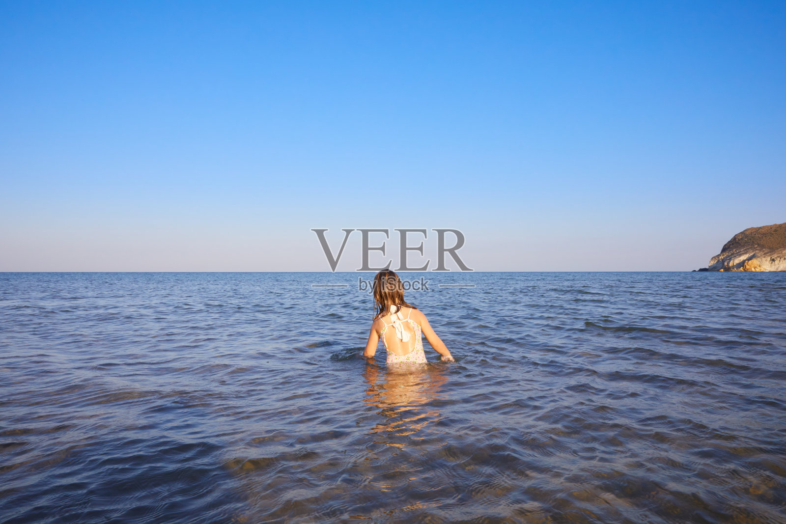 从一个小女孩的身后，在地中海的水里照片摄影图片