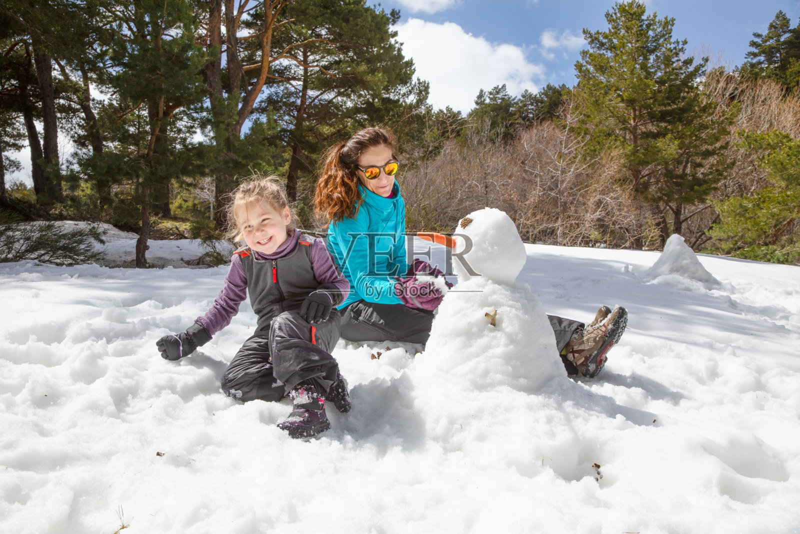快乐的小女孩和女人坐在森林里堆雪人照片摄影图片