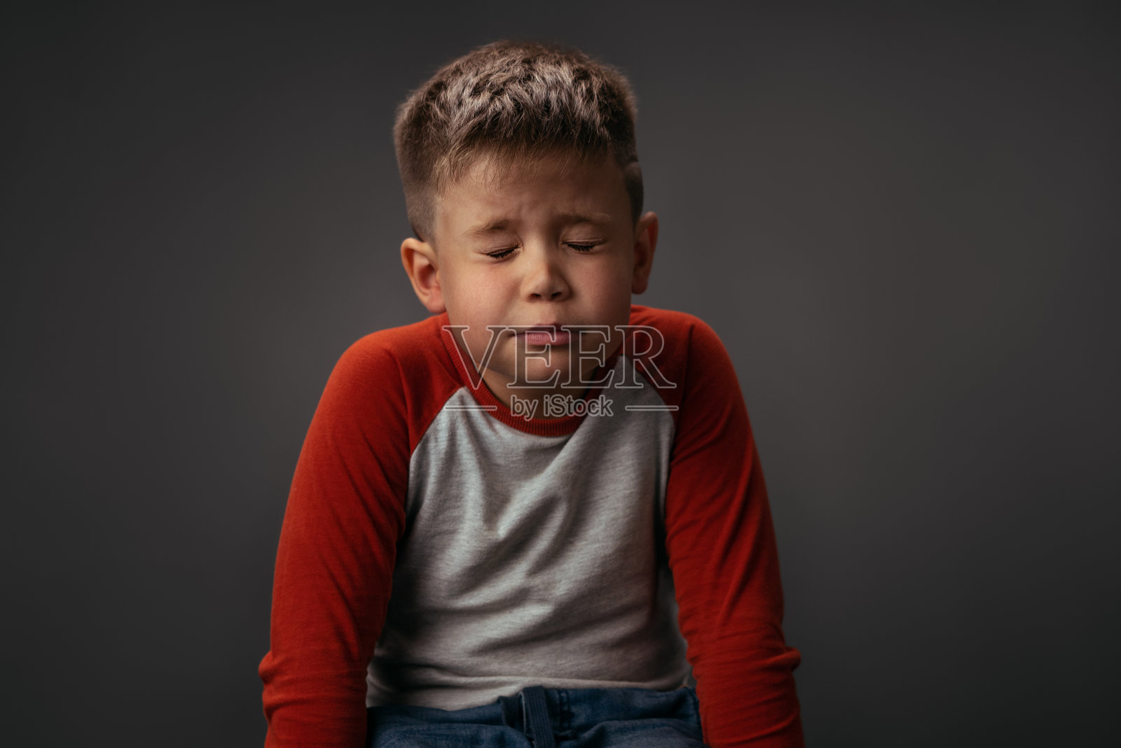 许个愿穿着红白衬衫的小男孩闭着眼睛坐在椅子上。为圣诞节许愿的概念。面部表情，情绪，感觉照片摄影图片