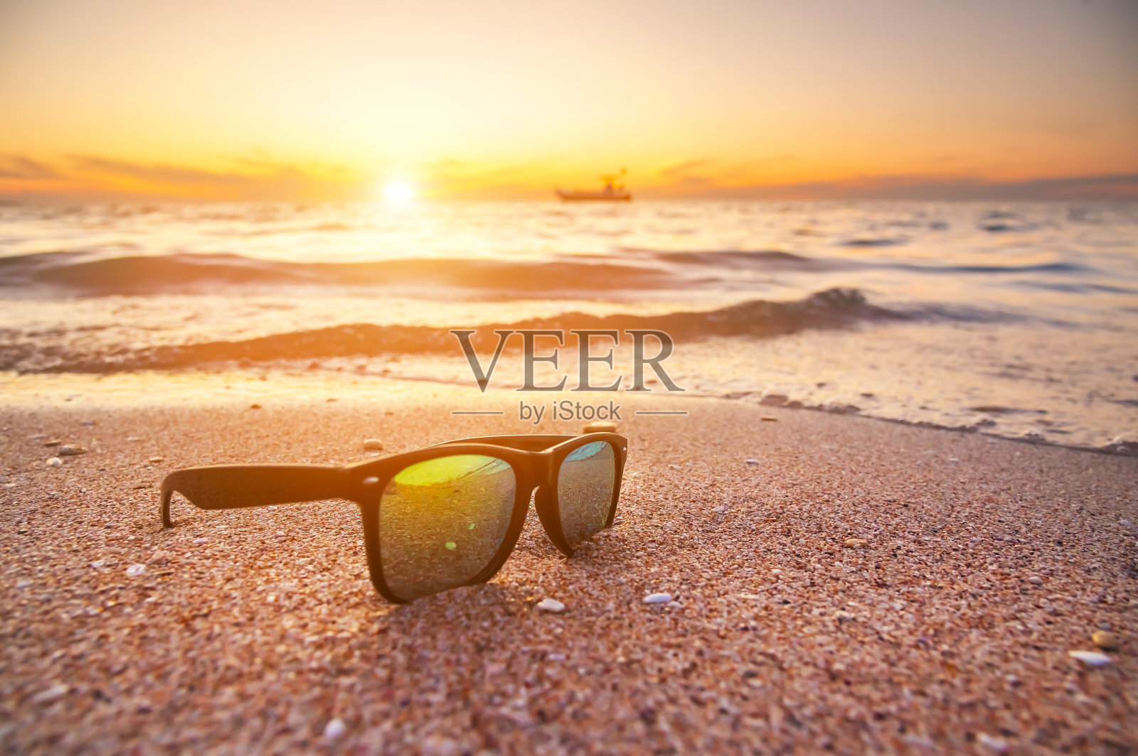 日落时，太阳镜躺在海边的沙滩上。假日和假期在海边照片摄影图片