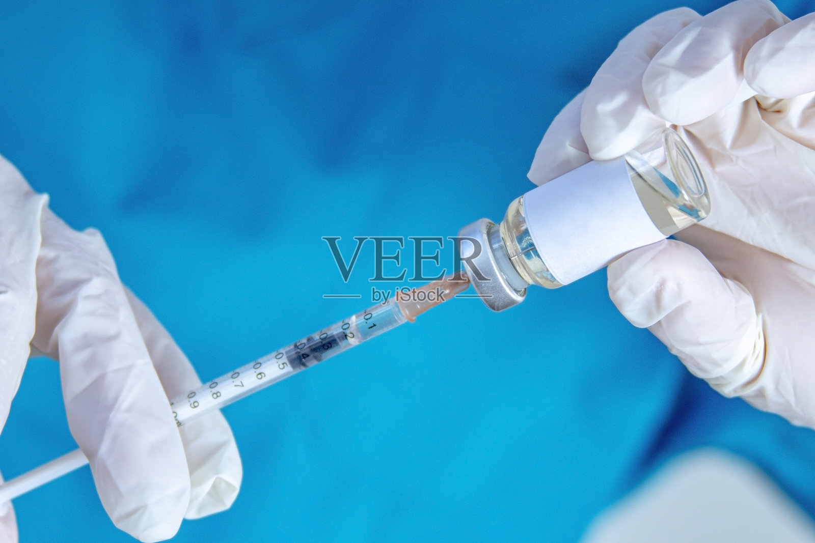 一个卫生工作者拿着一个注射器和一个小瓶疫苗，让它装满药物。照片摄影图片