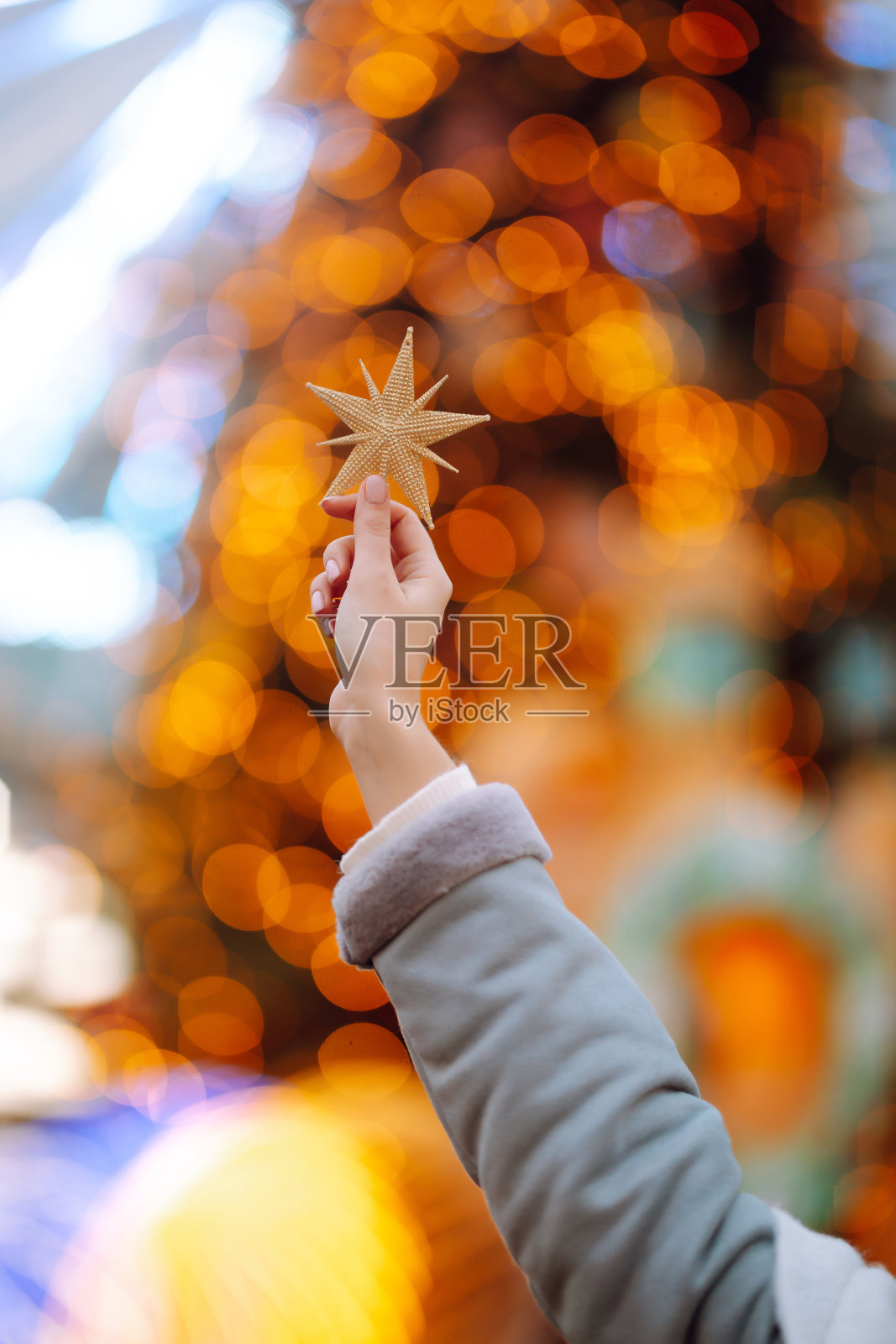 女人的手握着金色的五角星装饰。照片摄影图片