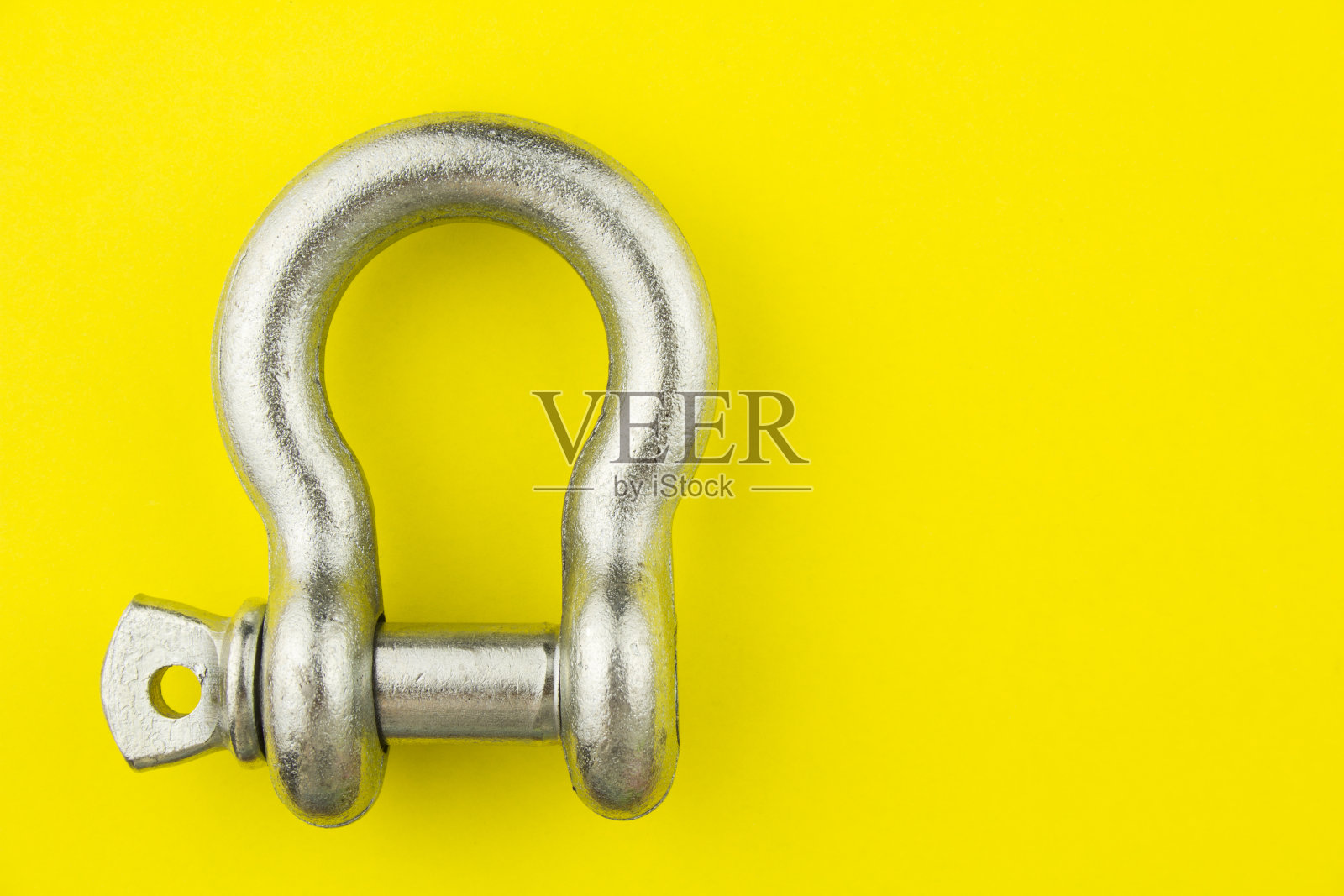 钢索具卸扣在黄色背景上，文字空白。照片摄影图片