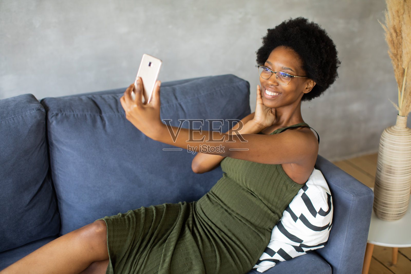 快乐的非洲裔美国年轻女子坐在舒适的沙发上放松高兴地搬到新公寓。微笑的黑人女孩休息在客厅舒适的沙发上做梦照片摄影图片