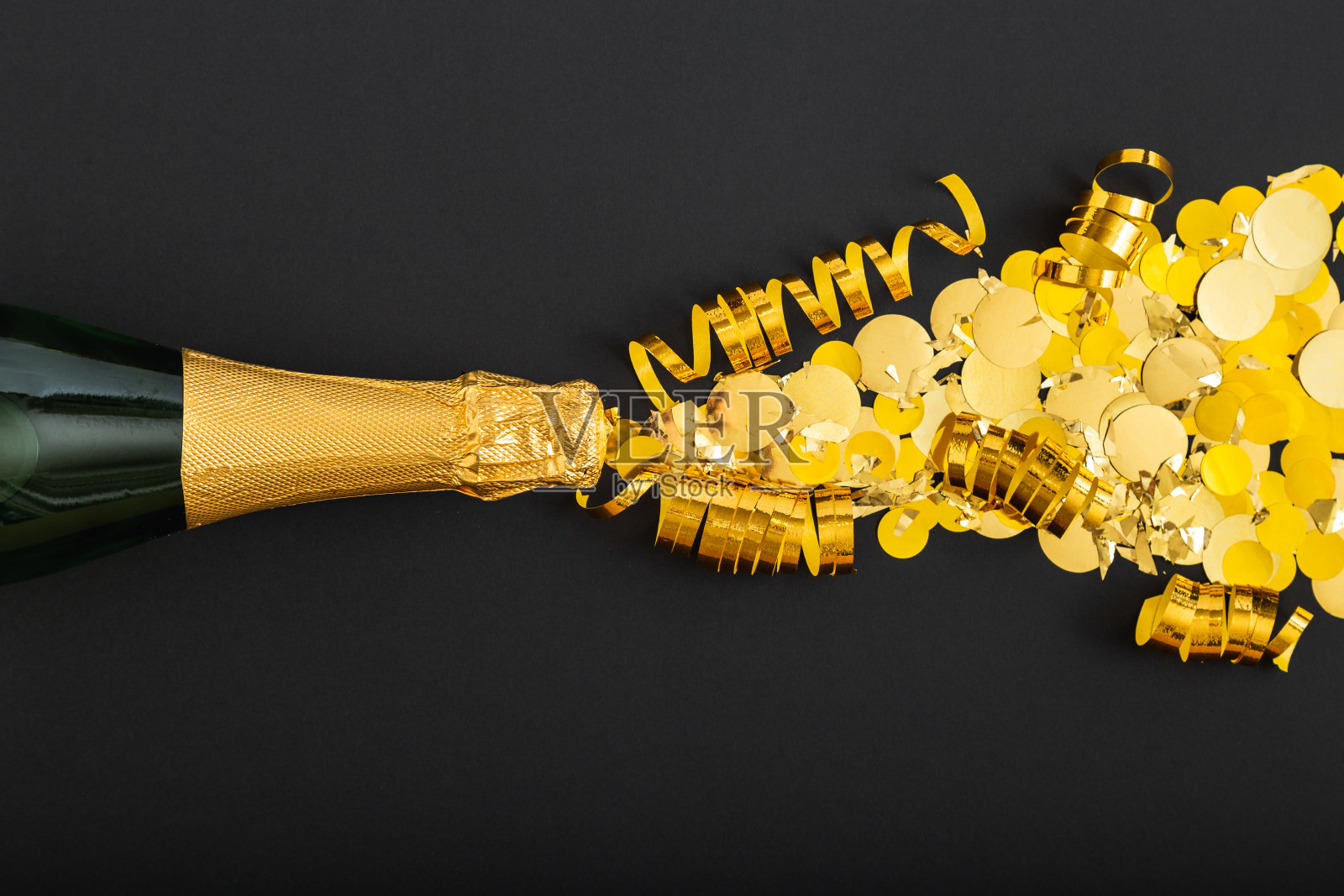 金色的香槟酒在黑色的背景上散发出金色的光芒。香槟闪光爆炸。平躺着新年前夕庆祝活动的黑暗背景照片摄影图片