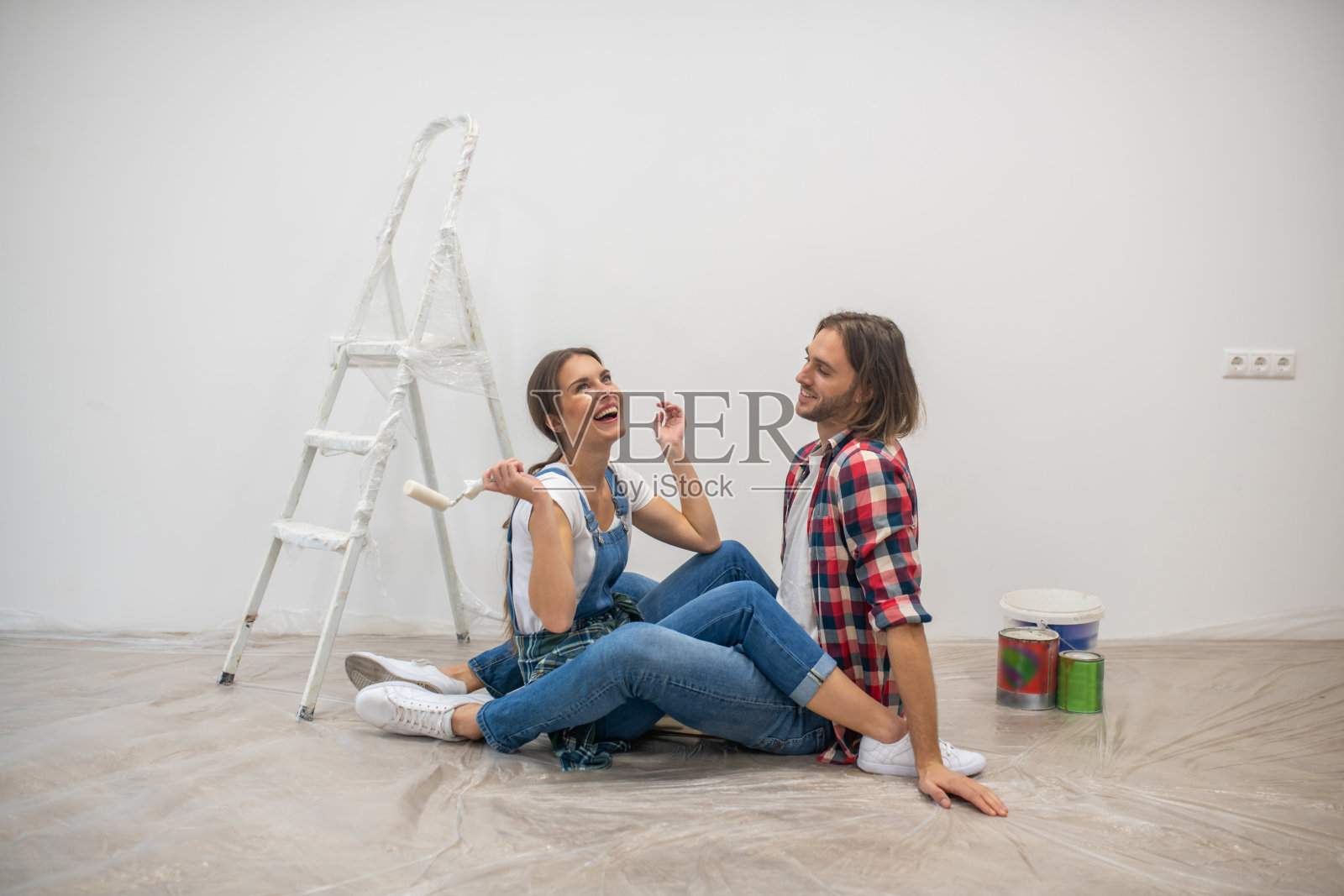 一对年轻夫妇坐在地板上，看起来很开心照片摄影图片