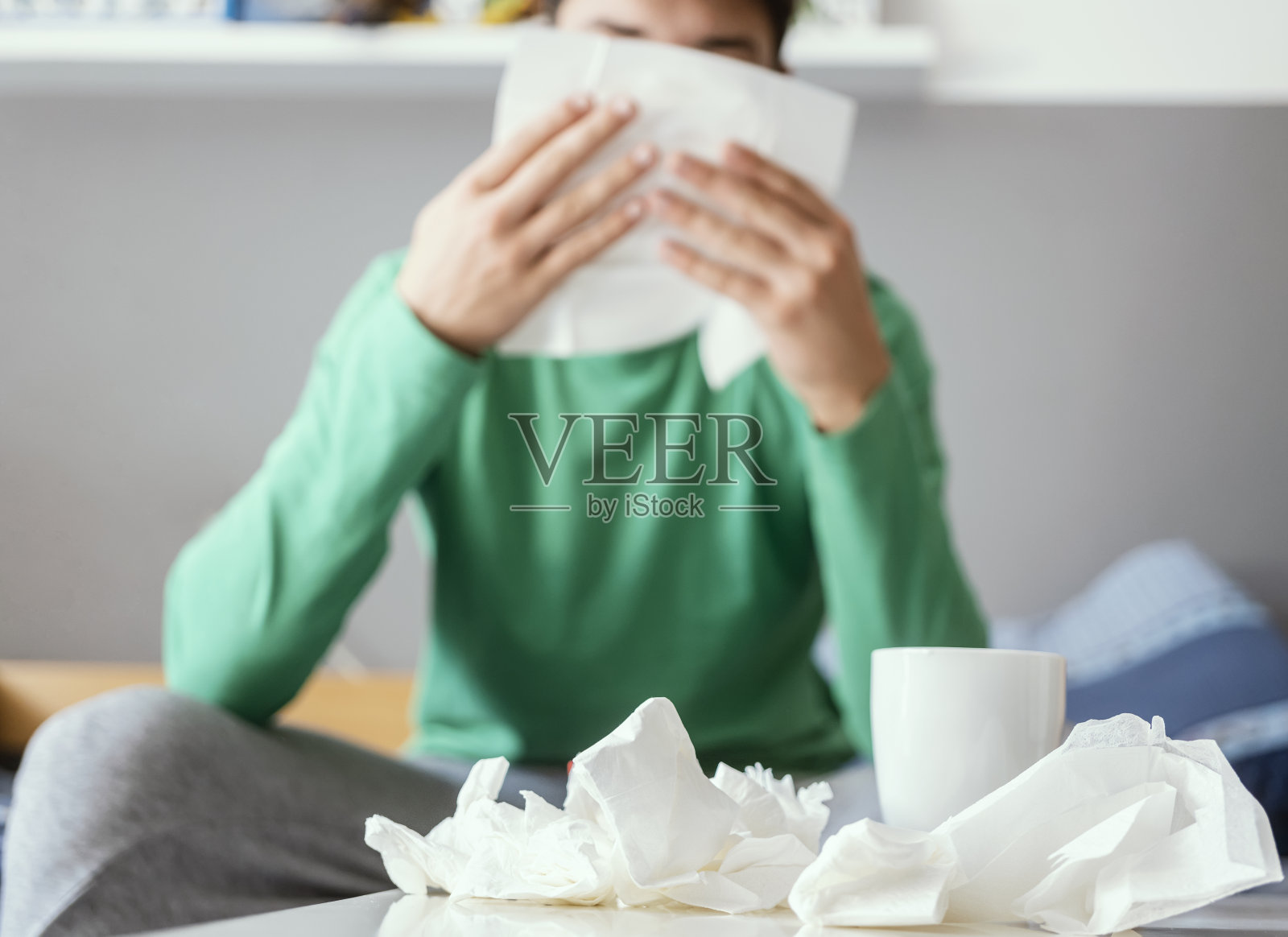 生病的小男孩坐在床上擤鼻涕照片摄影图片