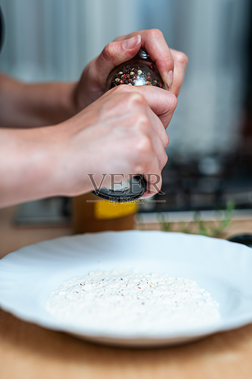 一个女人正在磨胡椒准备一顿饭。照片摄影图片