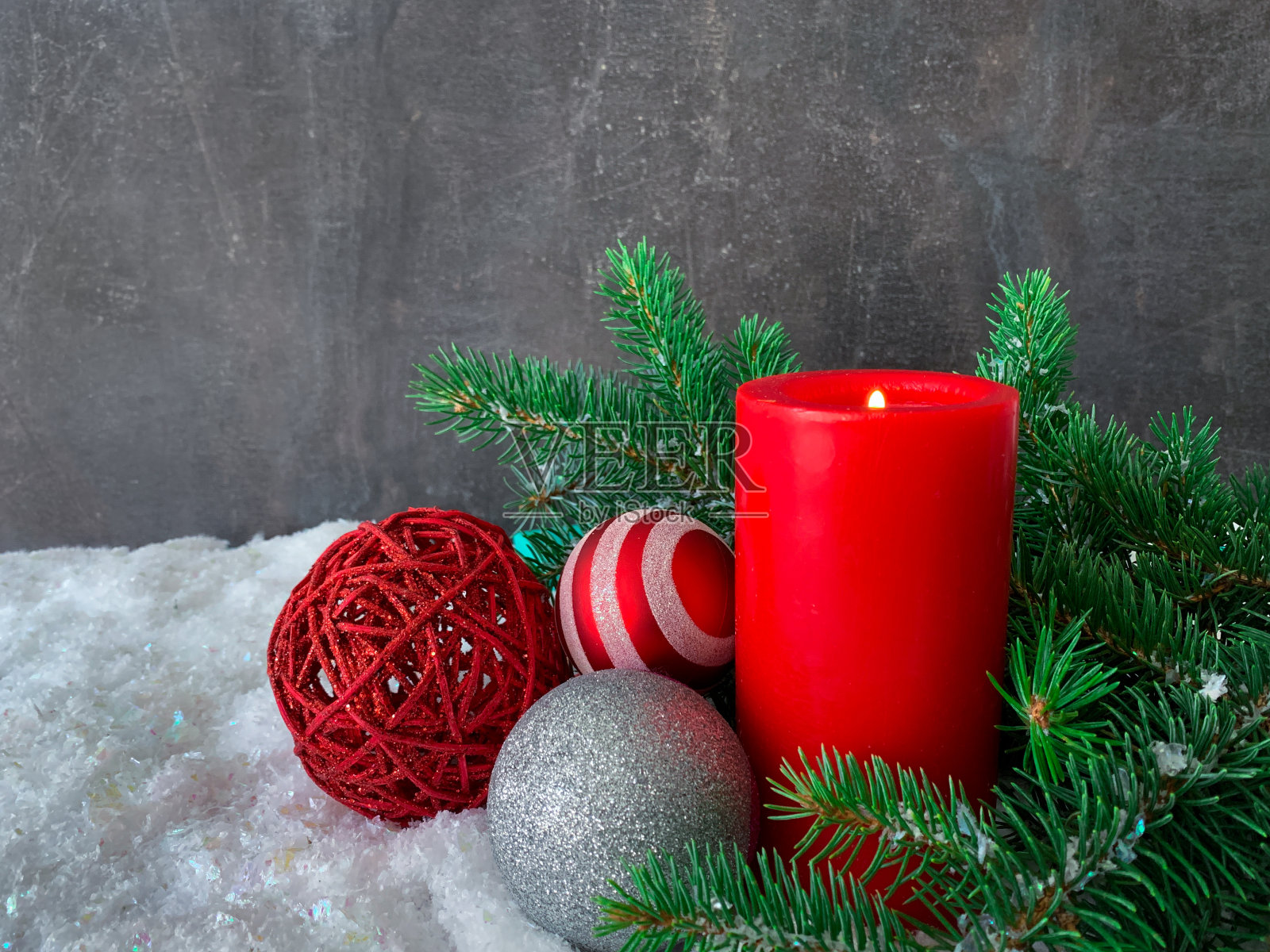 圣诞贺卡。节日气氛。红色的蜡烛与圣诞装饰和绿色的树枝在雪地上。照片摄影图片