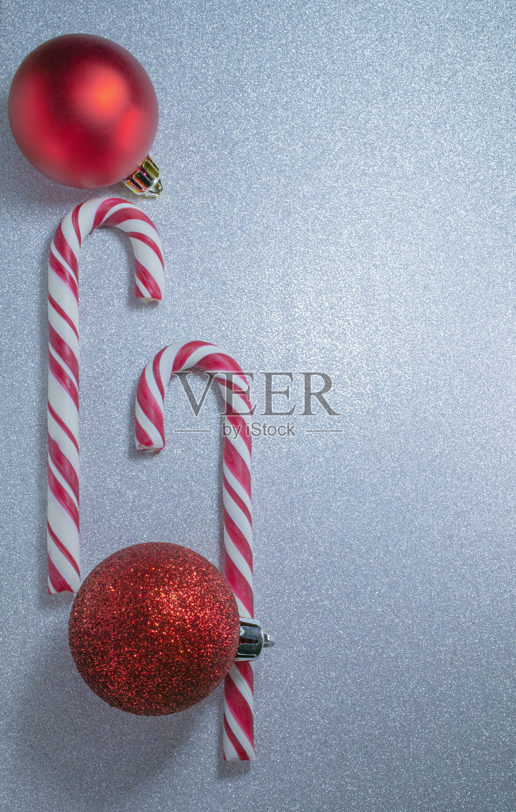 糖果拐杖和红色圣诞球闪闪发光的银色背景，选择性聚焦，复制空间。照片摄影图片