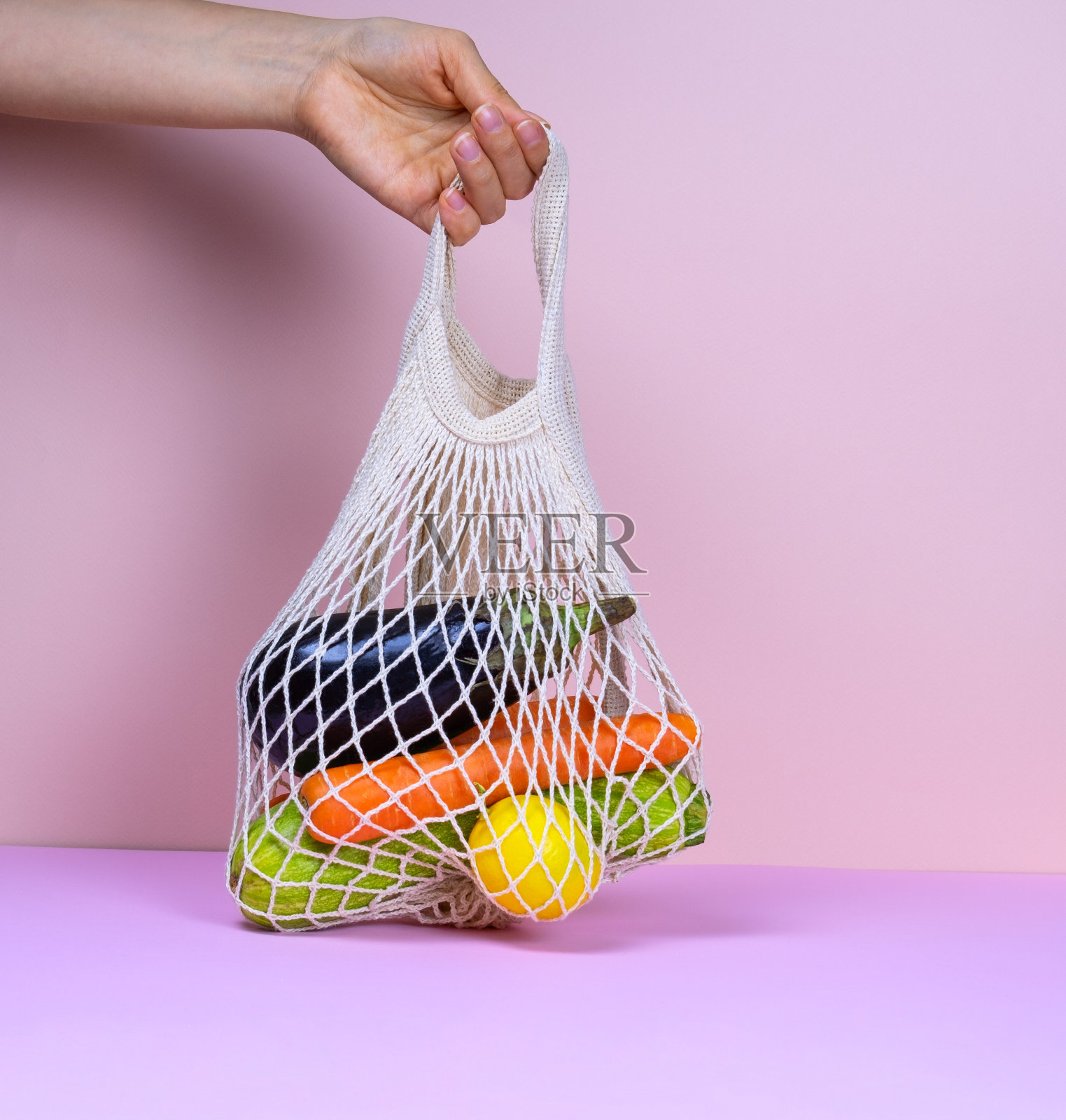 女手里拿着装满新鲜有机蔬菜的网袋照片摄影图片