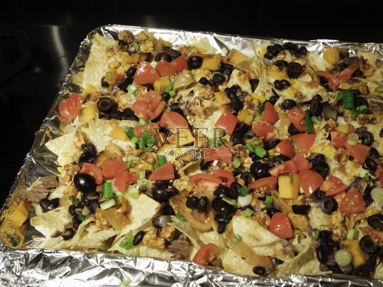 自制的烤盘里装着橄榄、新鲜番茄、大葱、奶酪、黑豆和肉照片摄影图片