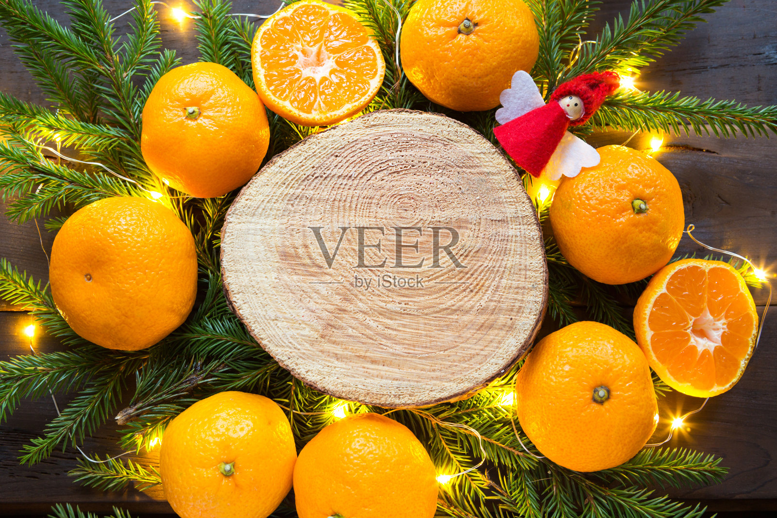 新年假日背景上剪圆的桔子树，活冷杉的树枝和金色的灯花环，用木制的空间为文字。柑橘的香气，一片片的橘子，圣诞的气息。框架照片摄影图片