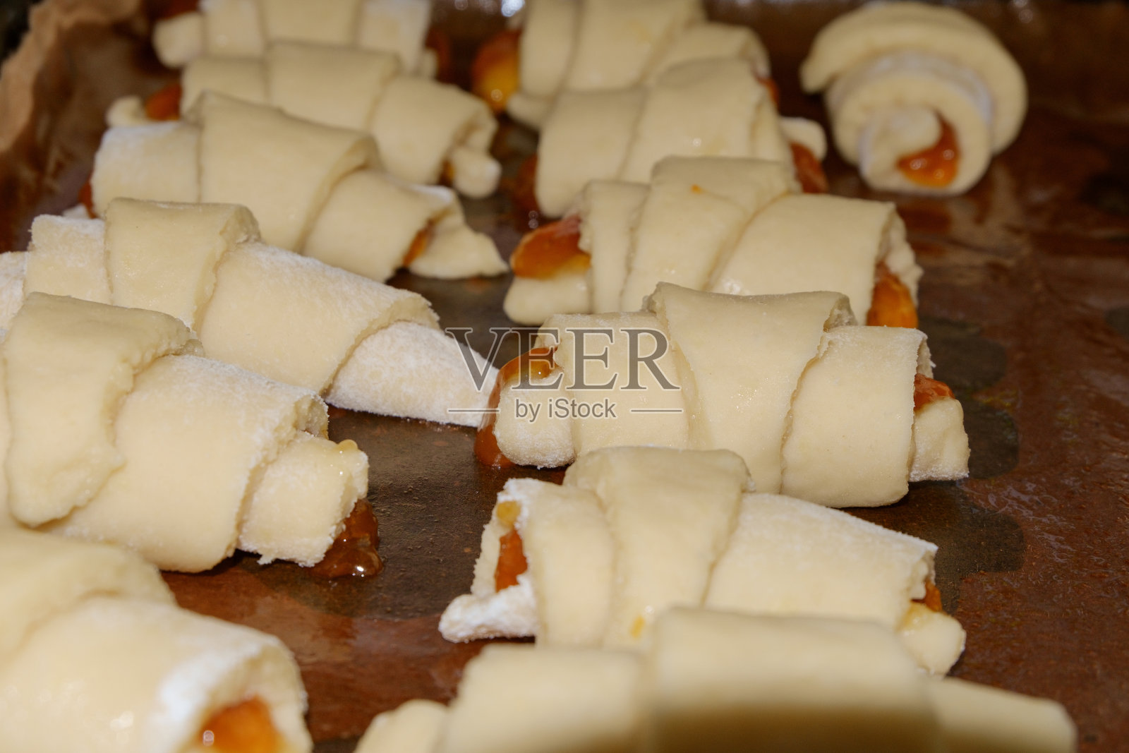 自制的饼干卷成管状，填满果酱，放在烤盘上照片摄影图片