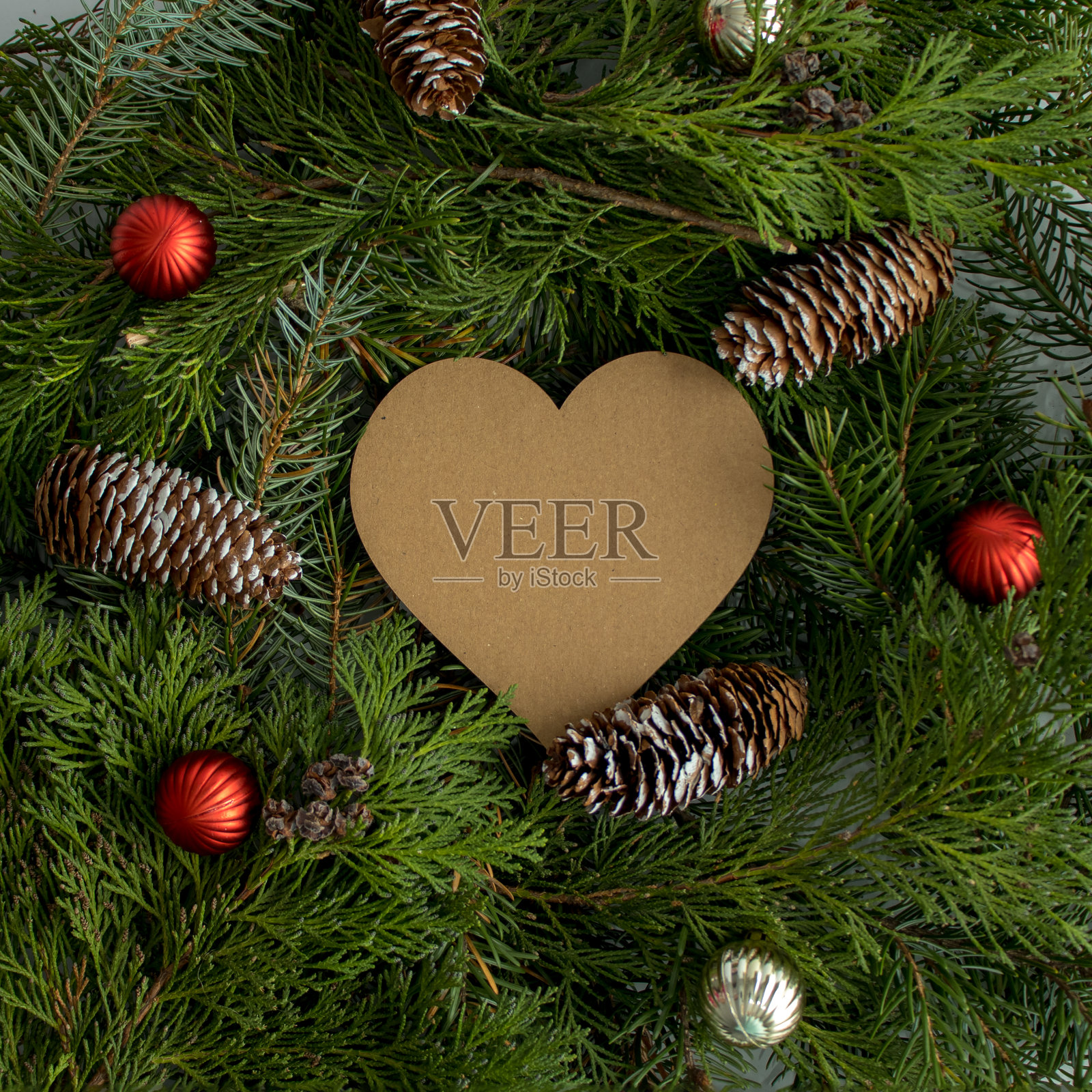 用圣诞树的树枝，心形的卡片，红色和银色的装饰球和锥形。新年的概念。平的。照片摄影图片