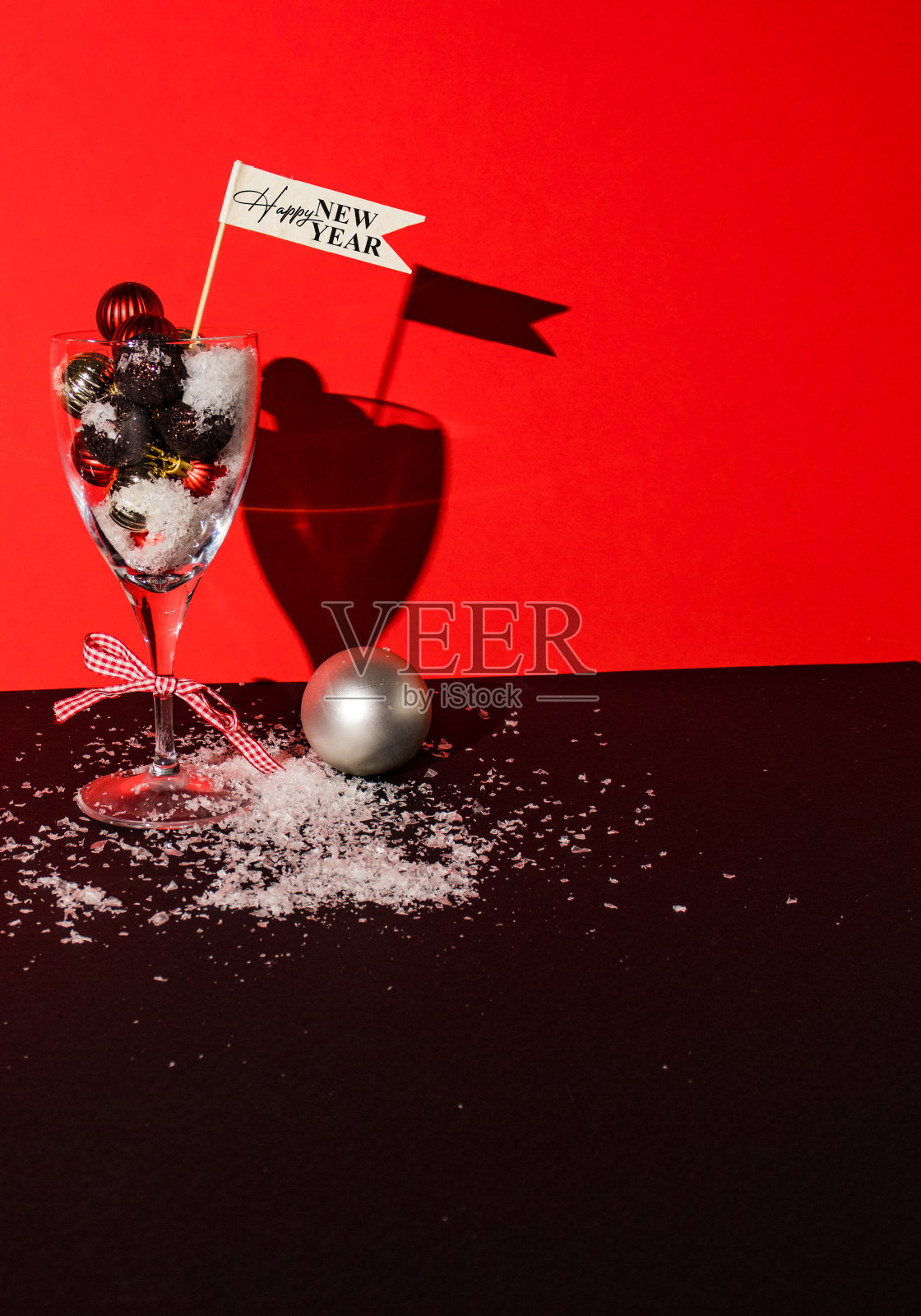 带有装饰球的酒杯放在黑色背景和雪上照片摄影图片