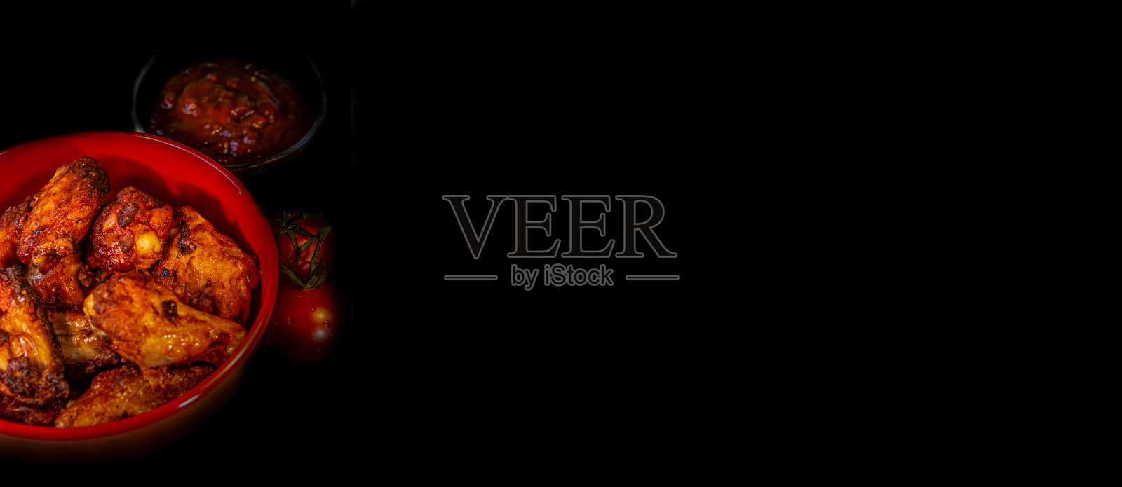 横幅烤鸡翅，烧烤酱和番茄在黑色背景与拷贝空间，特写，细节，黑暗设置。照片摄影图片