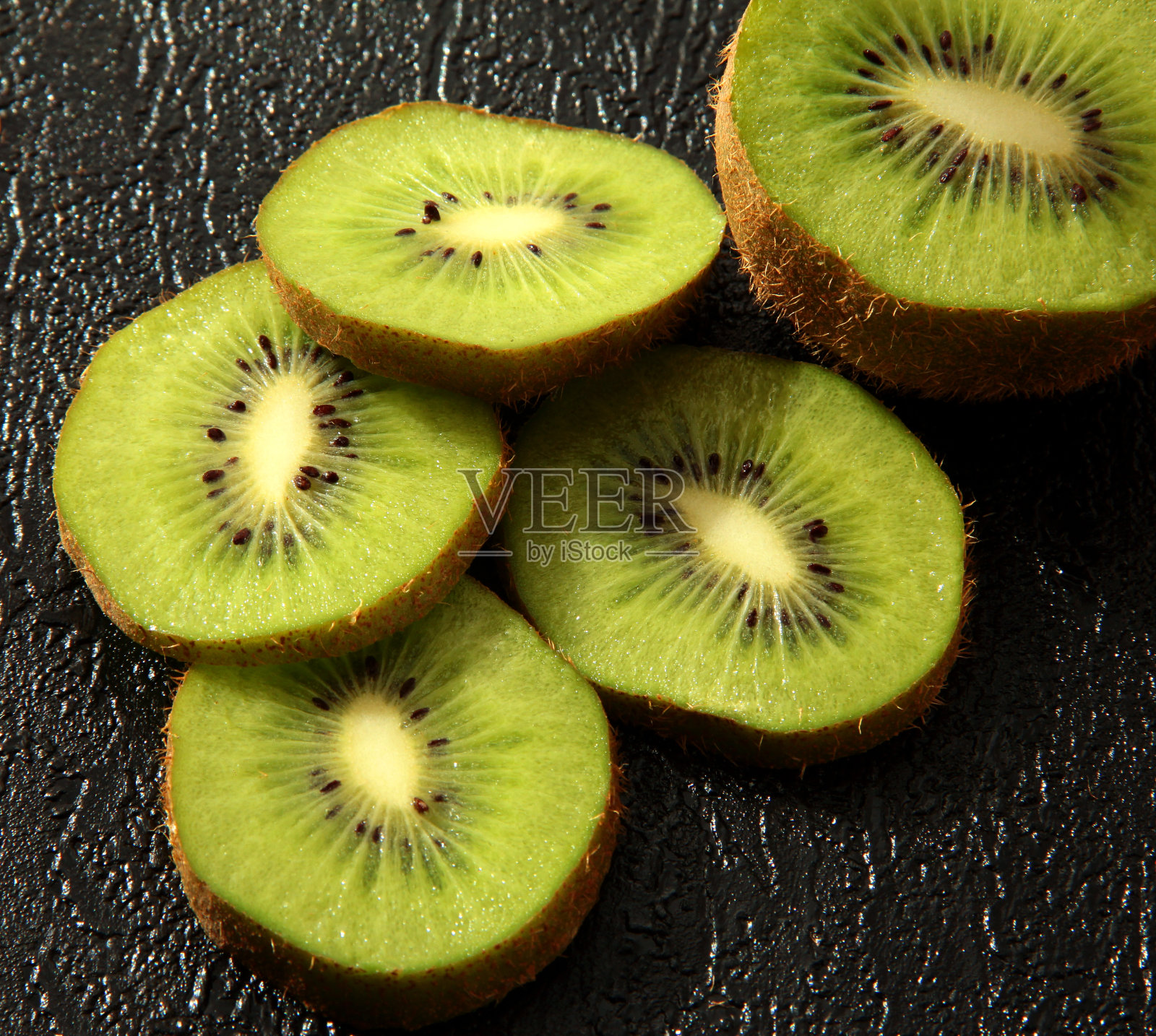 猕猴桃上的黑色纹理背景。多汁的水果。照片摄影图片