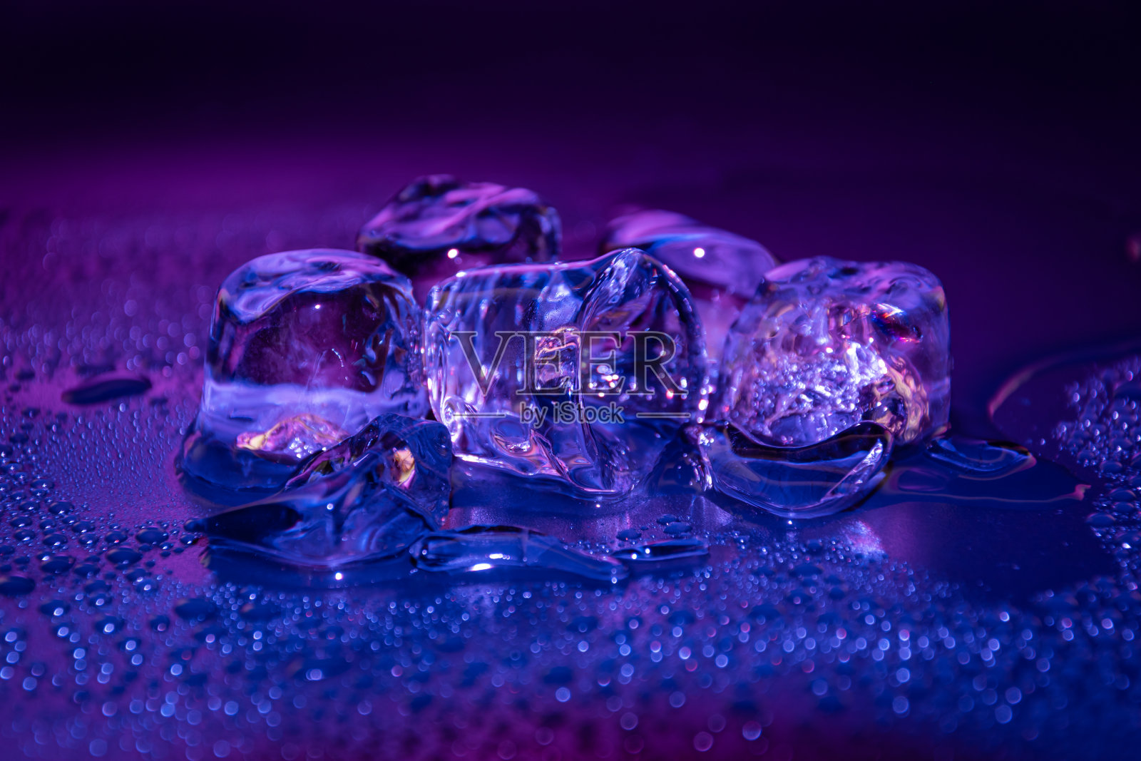 在黑暗中，用渐变的彩色LED灯照亮融化的冰块。照片摄影图片