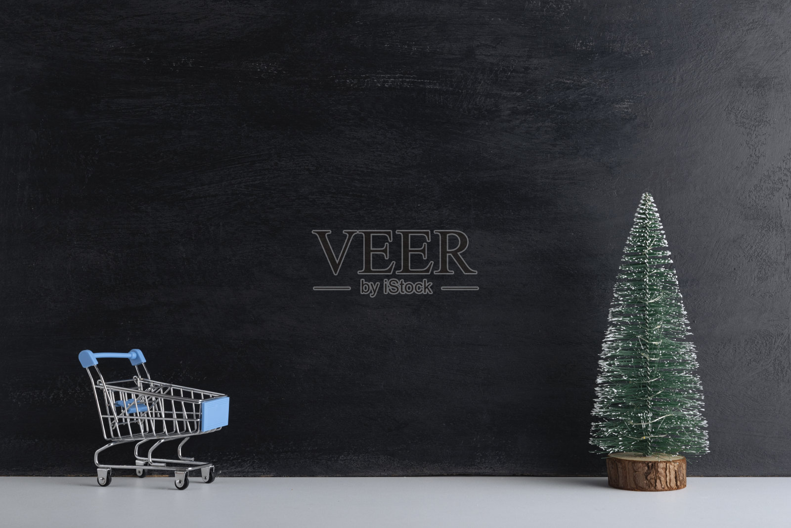 购物车和微型圣诞树在黑色的背景。新年购物。本空间照片摄影图片