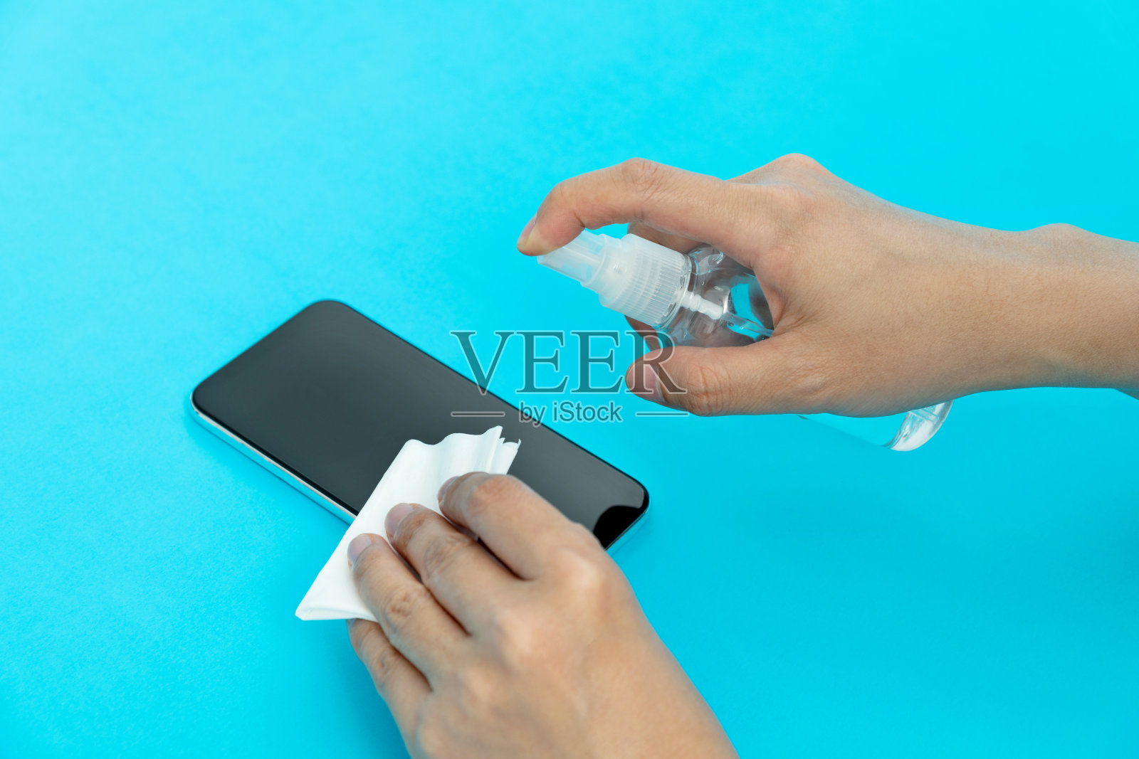 在蓝色背景上清洁智能手机的女人照片摄影图片