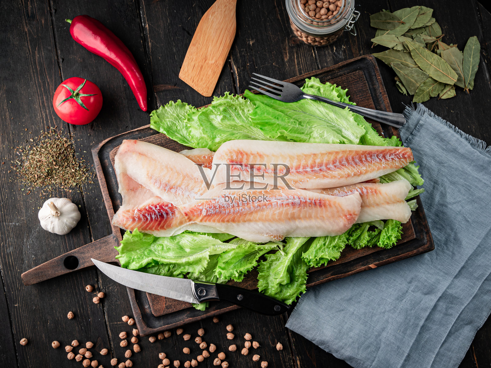 新鲜的青鳕片和烹饪材料放在木砧板上。照片摄影图片