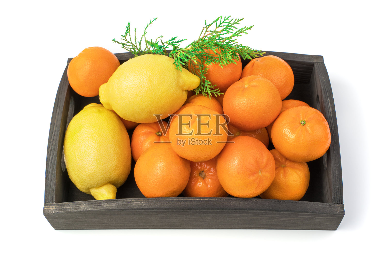 橘子和柠檬装在一个有针叶树枝的盒子里，孤立在白色的背景上。照片摄影图片