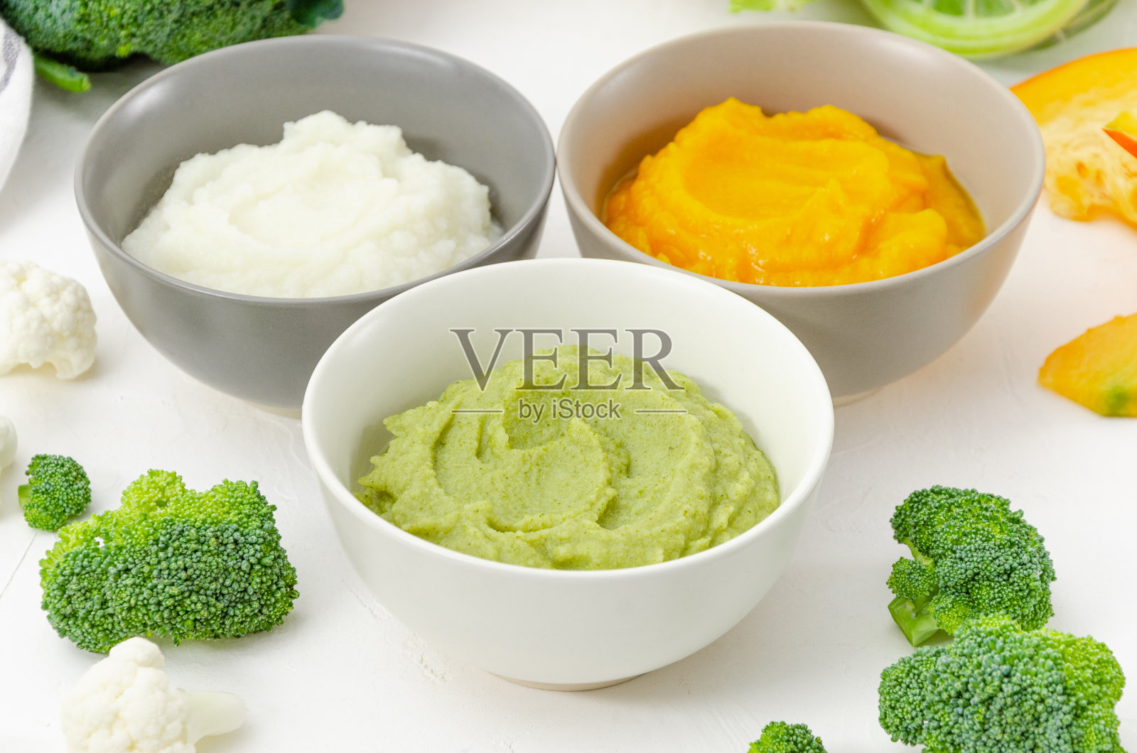 婴儿食品。变异的三碗自制蔬菜泥。南瓜泥，花椰菜泥和西兰花泥在白色的背景。照片摄影图片