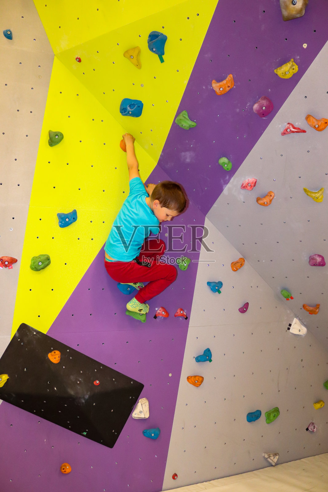 一个小男孩在爬抱石墙上照片摄影图片